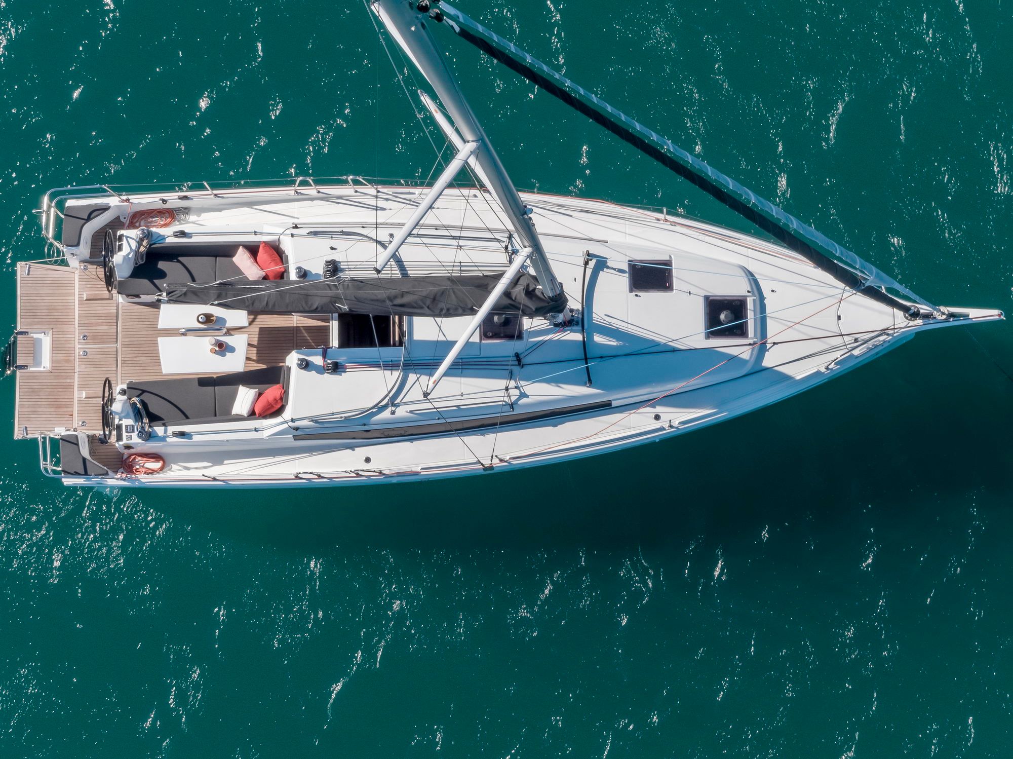 Widok z góry na jacht żaglowy Jeanneau Sun Odyssey 380 na wodzie. Widać przestronny pokład, kokpit z podwójnymi kołami sterowymi i maszt.