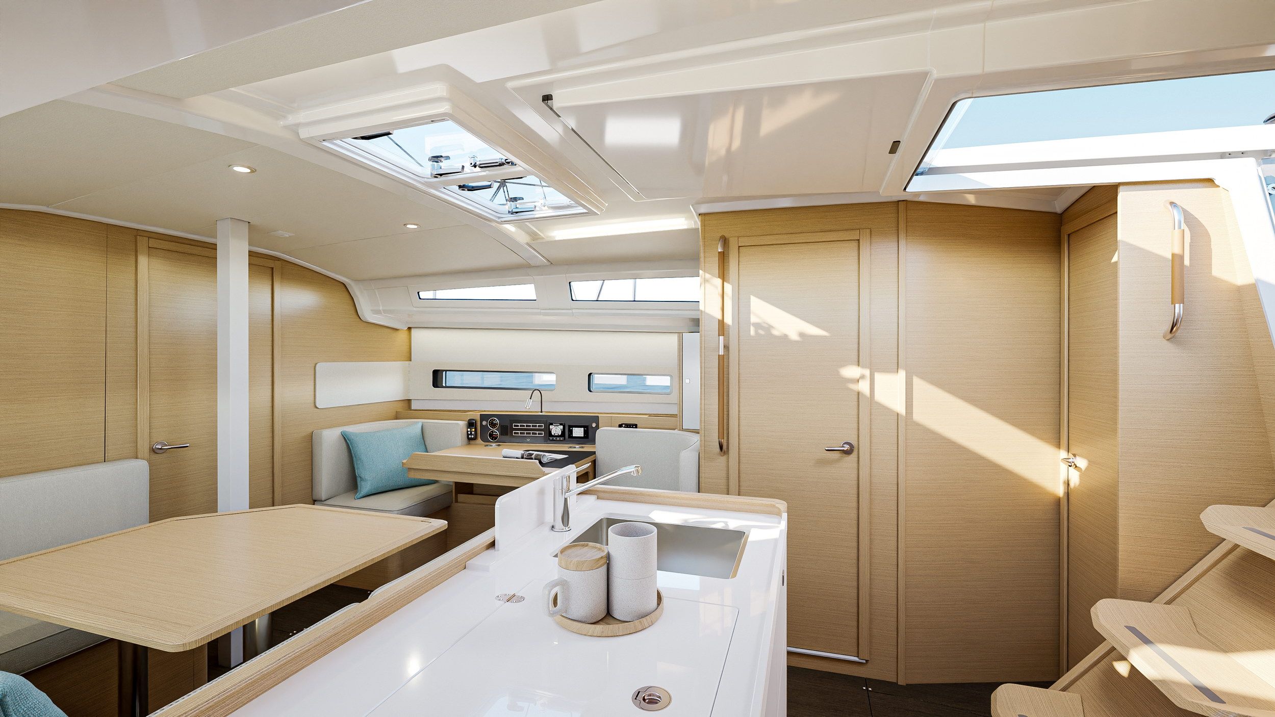 Wnętrze jachtu Jeanneau Sun Odyssey 415 z salonem, stołem jadalnym, kambuzem i schodami prowadzącymi w dół.