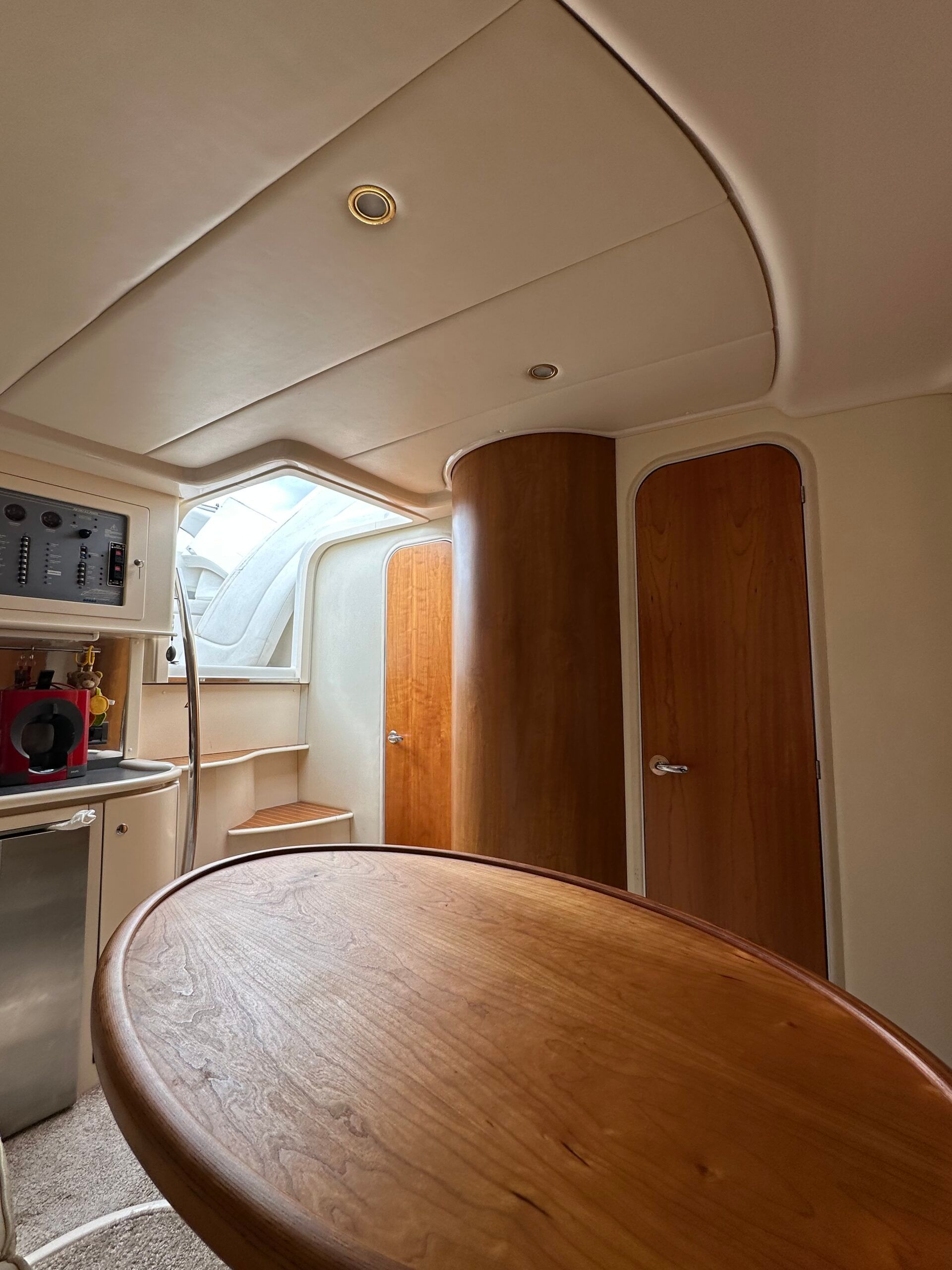 Innenraum der Sessa 35 Oyster Motoryacht, Blick auf den Salon mit Holztisch, Bedienpanel und Kabinentüren.