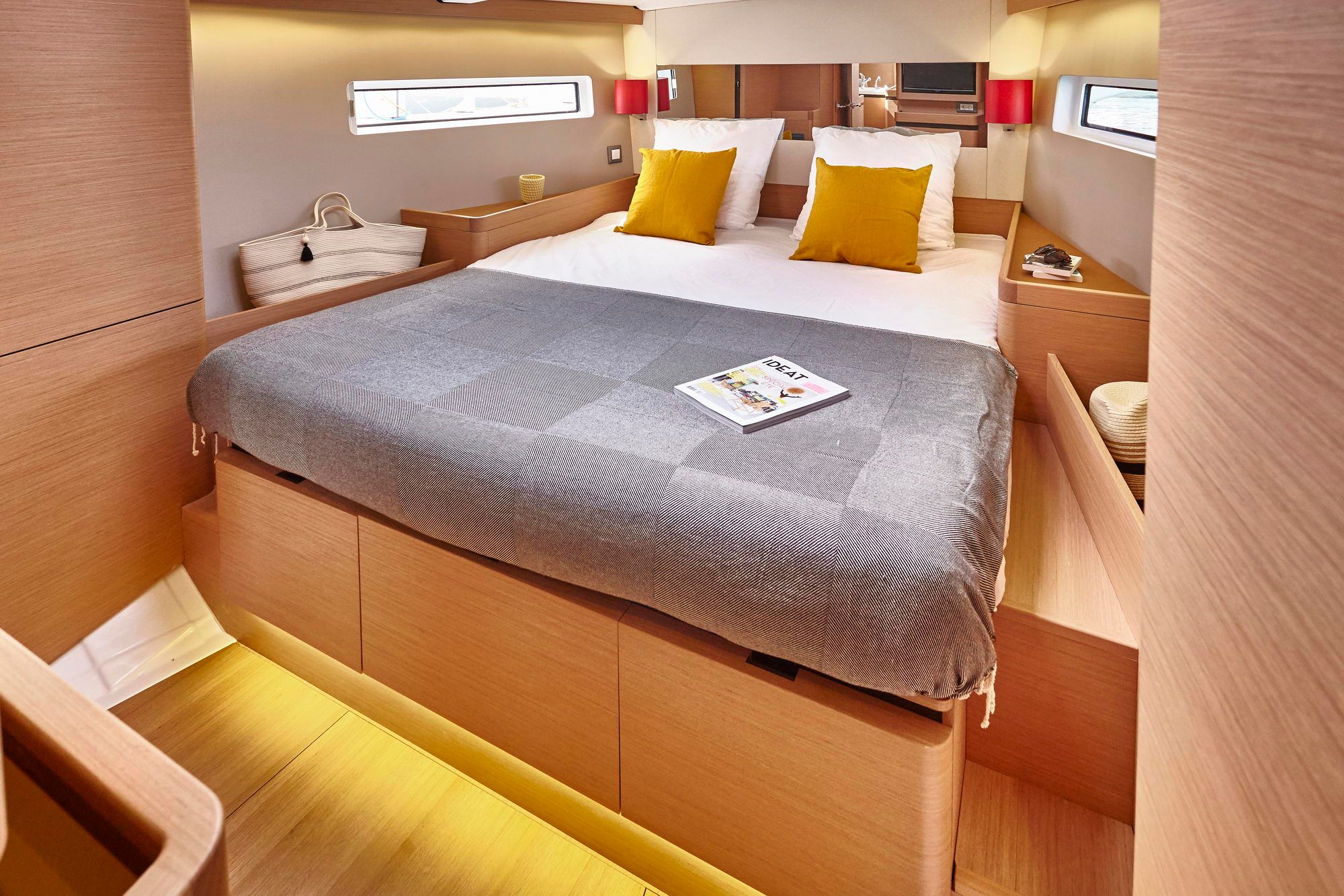 Geräumige Bugkabine der Jeanneau Sun Odyssey 490 mit großem Bett, Fenstern und Holzmöbeln.