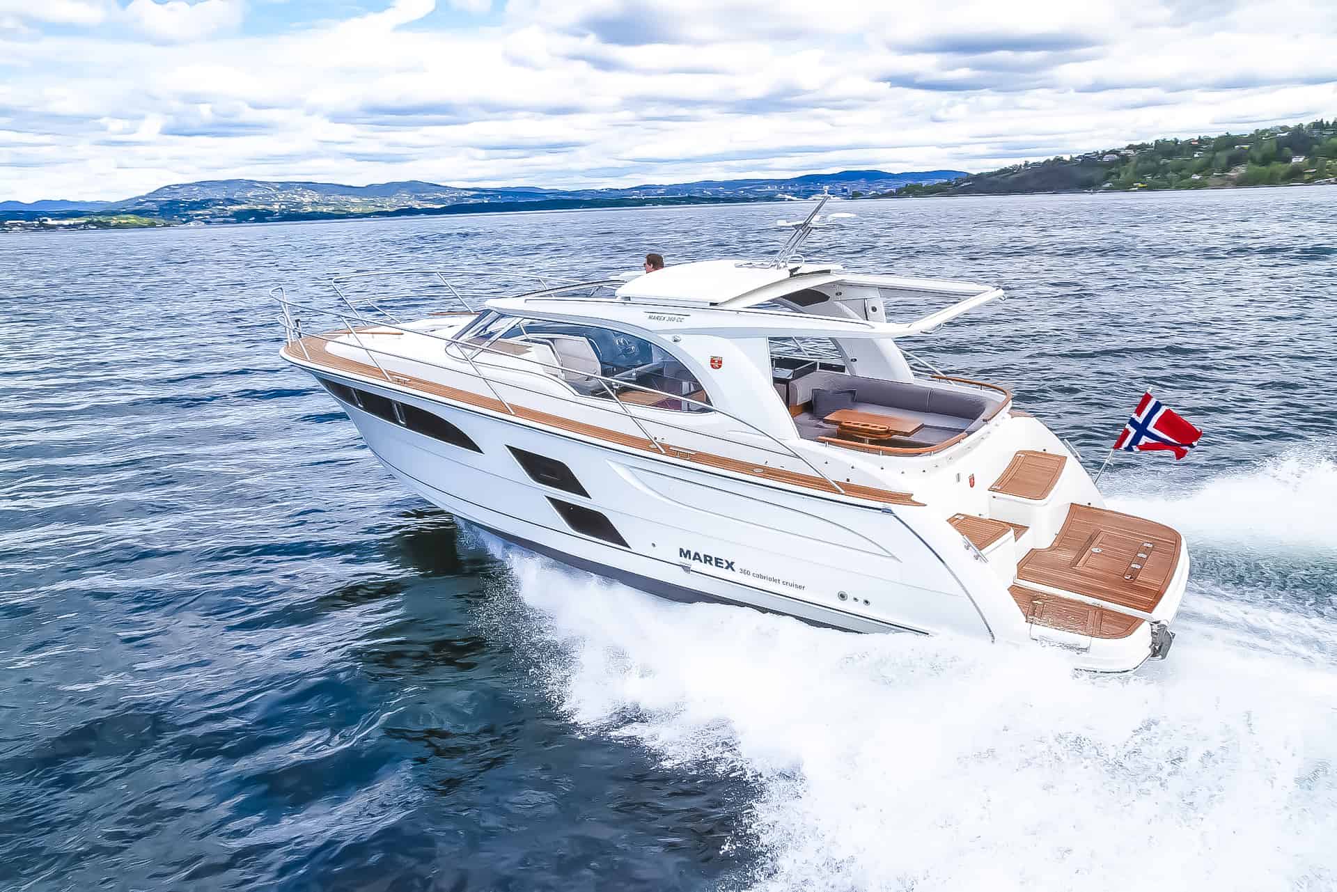 Biały jacht motorowy Marex 360 Cabriolet Cruiser płynący po wodzie, z widocznym zadaszeniem i drewnianymi detalami.
