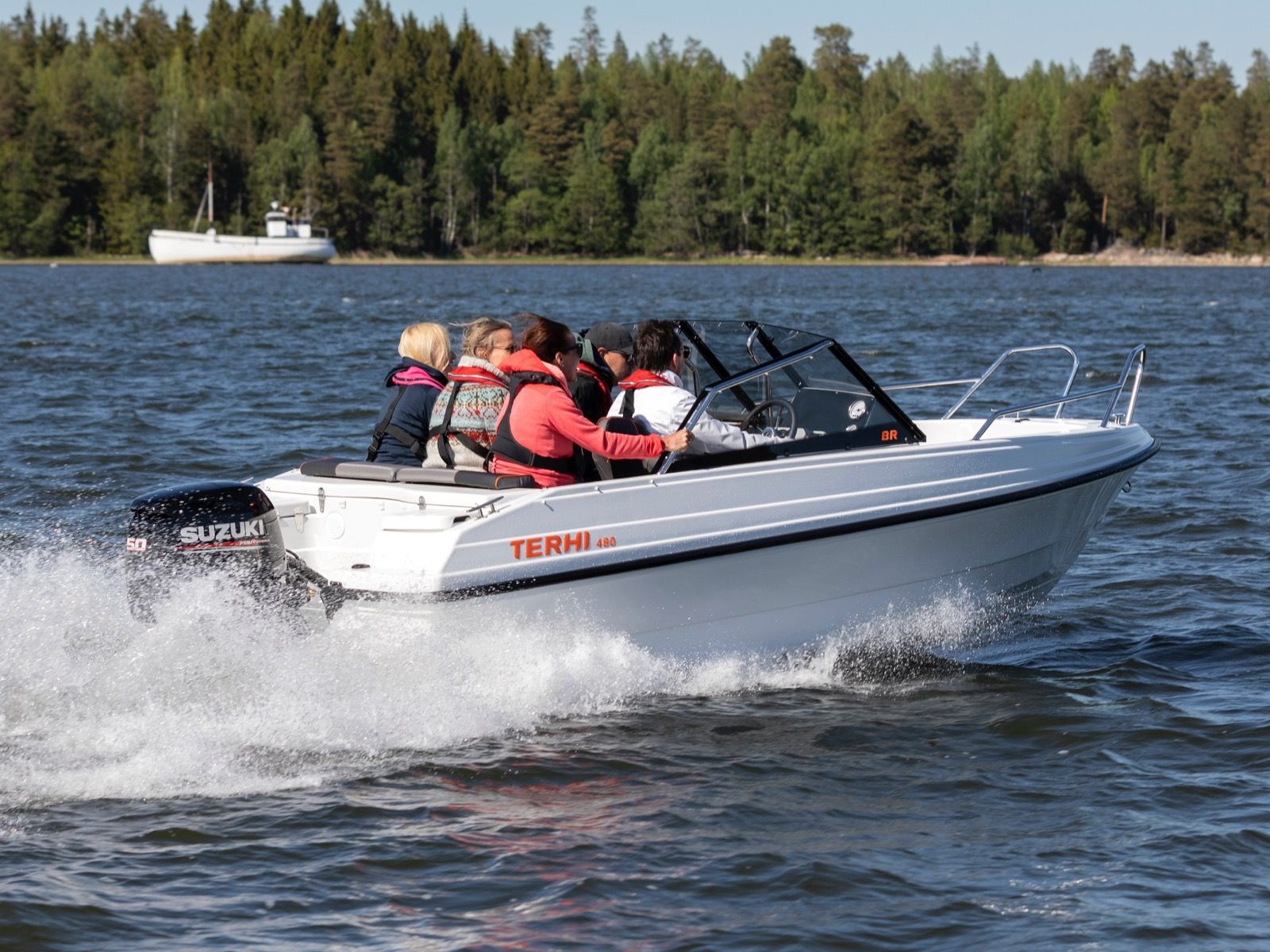 Biała łódź motorowa Terhi 480 BR z silnikiem Suzuki 50 KM, płynąca po jeziorze z pasażerami.