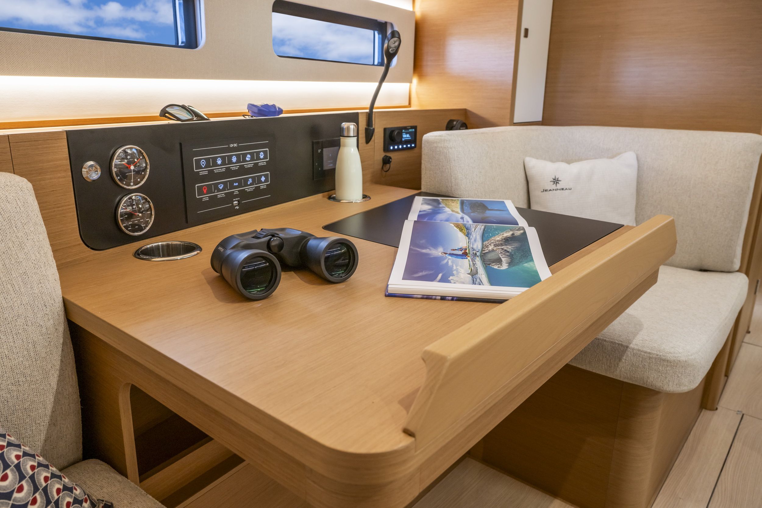 Stacja nawigacyjna z drewnianym biurkiem, lornetką i panelem sterowania w kabinie jachtu Jeanneau Sun Odyssey 415.
