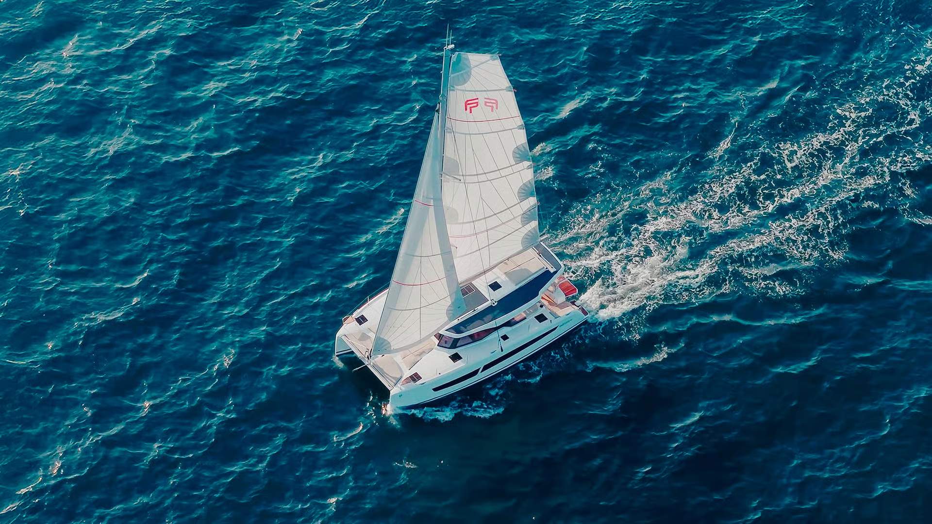 Luftaufnahme des Segelkatamarans Fountaine Pajot FP41 auf bewegter See mit gesetzten Segeln.