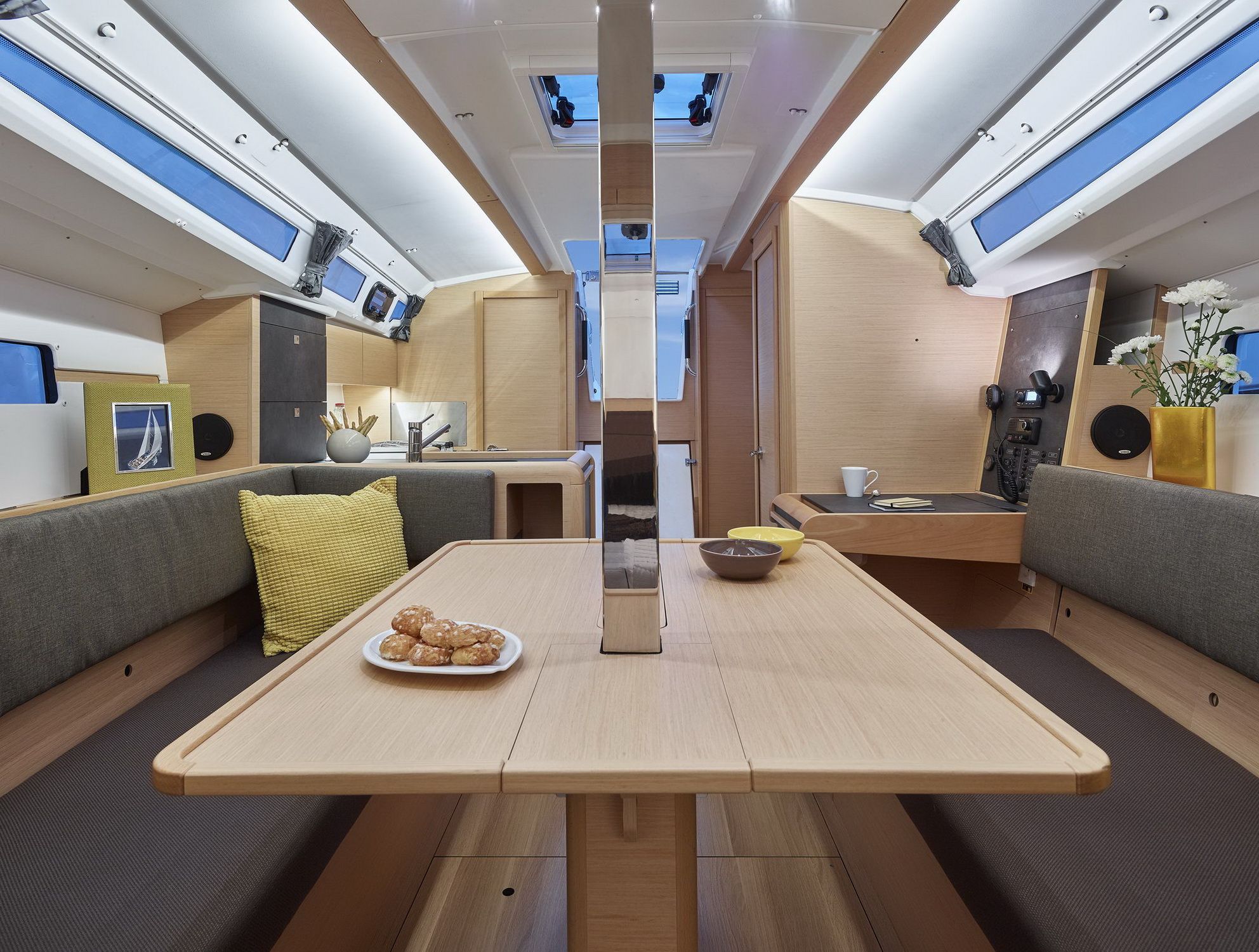 Wnętrze jachtu żaglowego Jeanneau Sun Odyssey 349, przedstawiające salon, kambuz i stolik nawigacyjny.