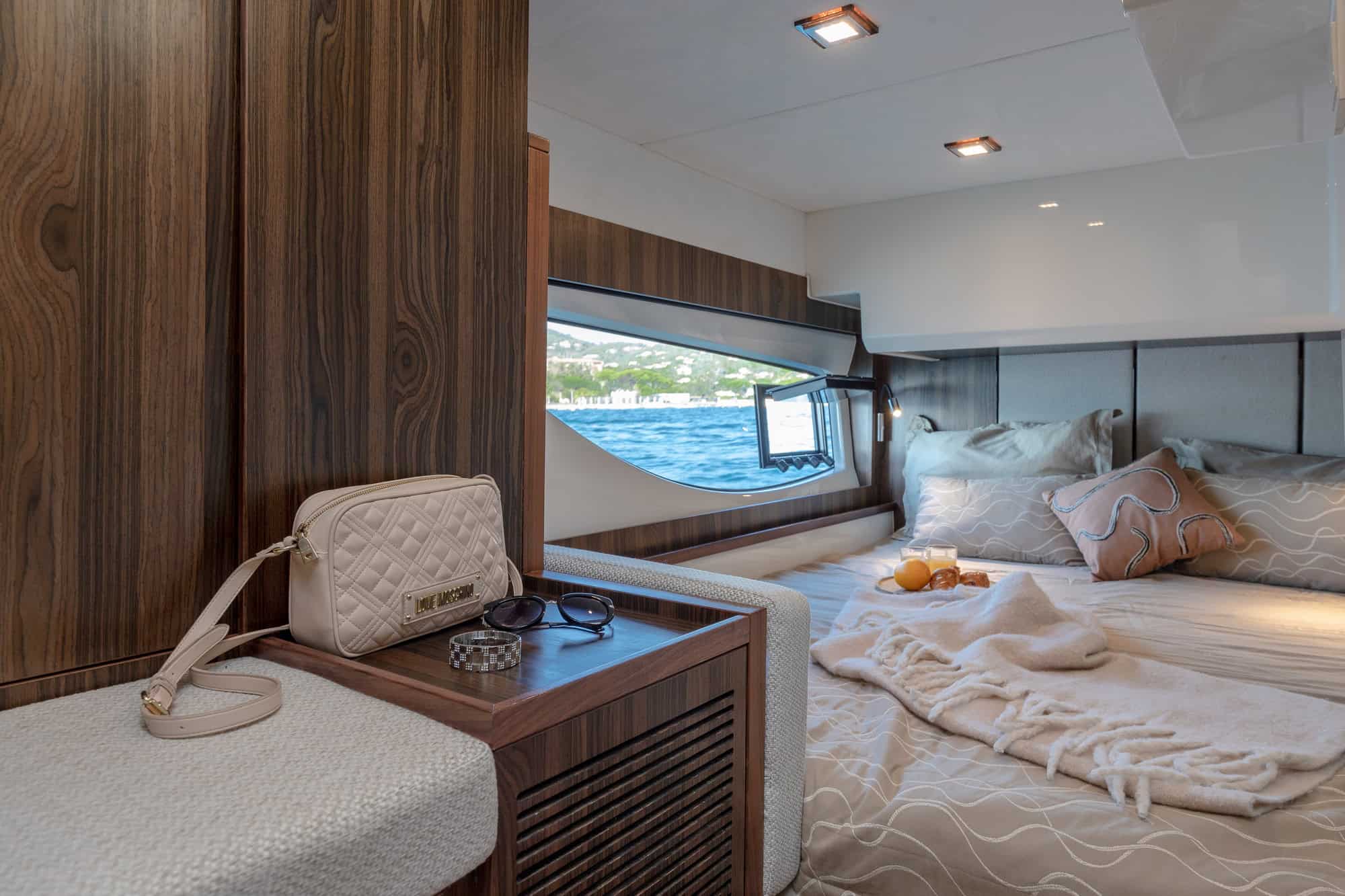 Interior of a sleeping cabin on the Marex 440 Gourmet Cruiser with large bed, wood panelling and a window with a sea view.