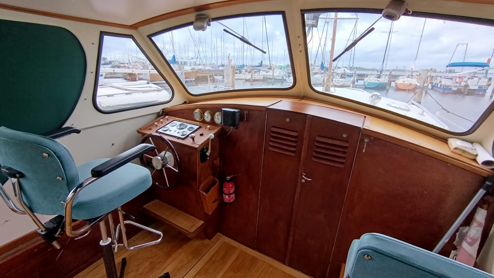 Wnętrze kabiny sternika jachtu motorowego Aquanaut 750 z widokiem na kokpit, kierownicę, panel sterowania i fotel sternika.