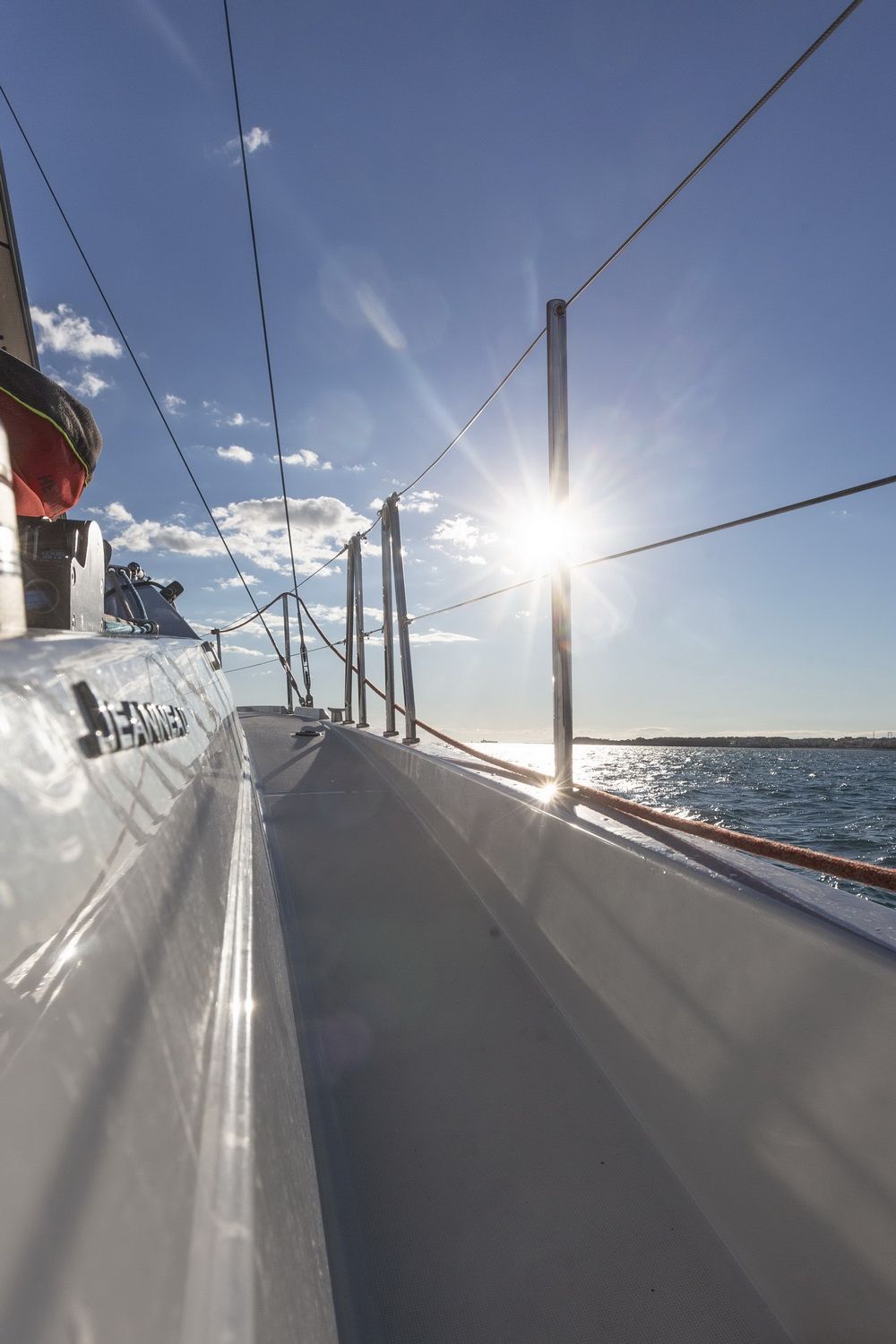 View of the side deck on the Jeanneau Sun Odyssey 380 on a sunny day, with logo and sea visible.