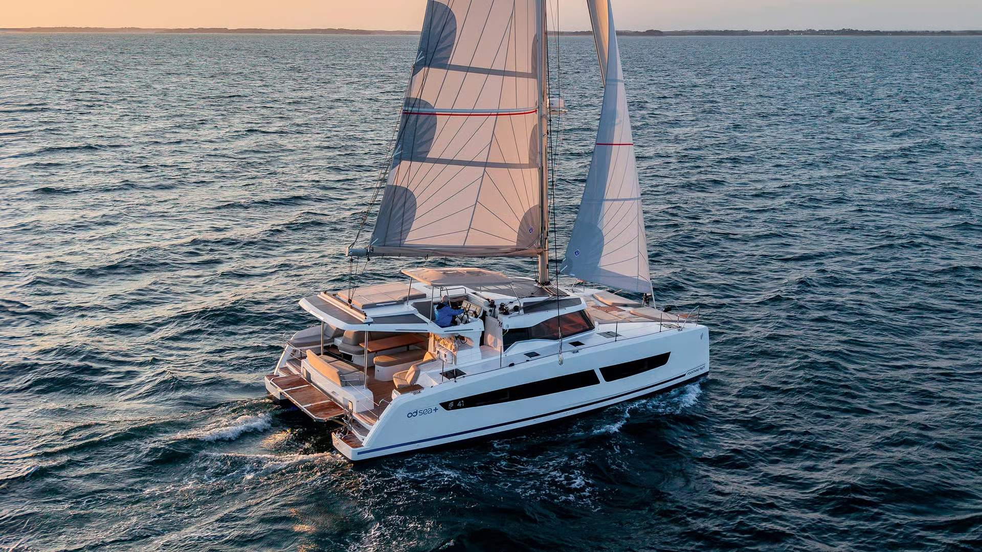 Katamaran żaglowy Fountaine Pajot FP41 płynący po otwartym morzu o zachodzie słońca, widok z tyłu.