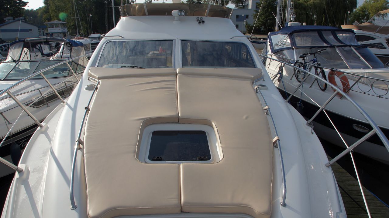 View of the bow of the Sealine F44 Flybridge motor yacht with beige sunbathing cushions and a deck hatch.