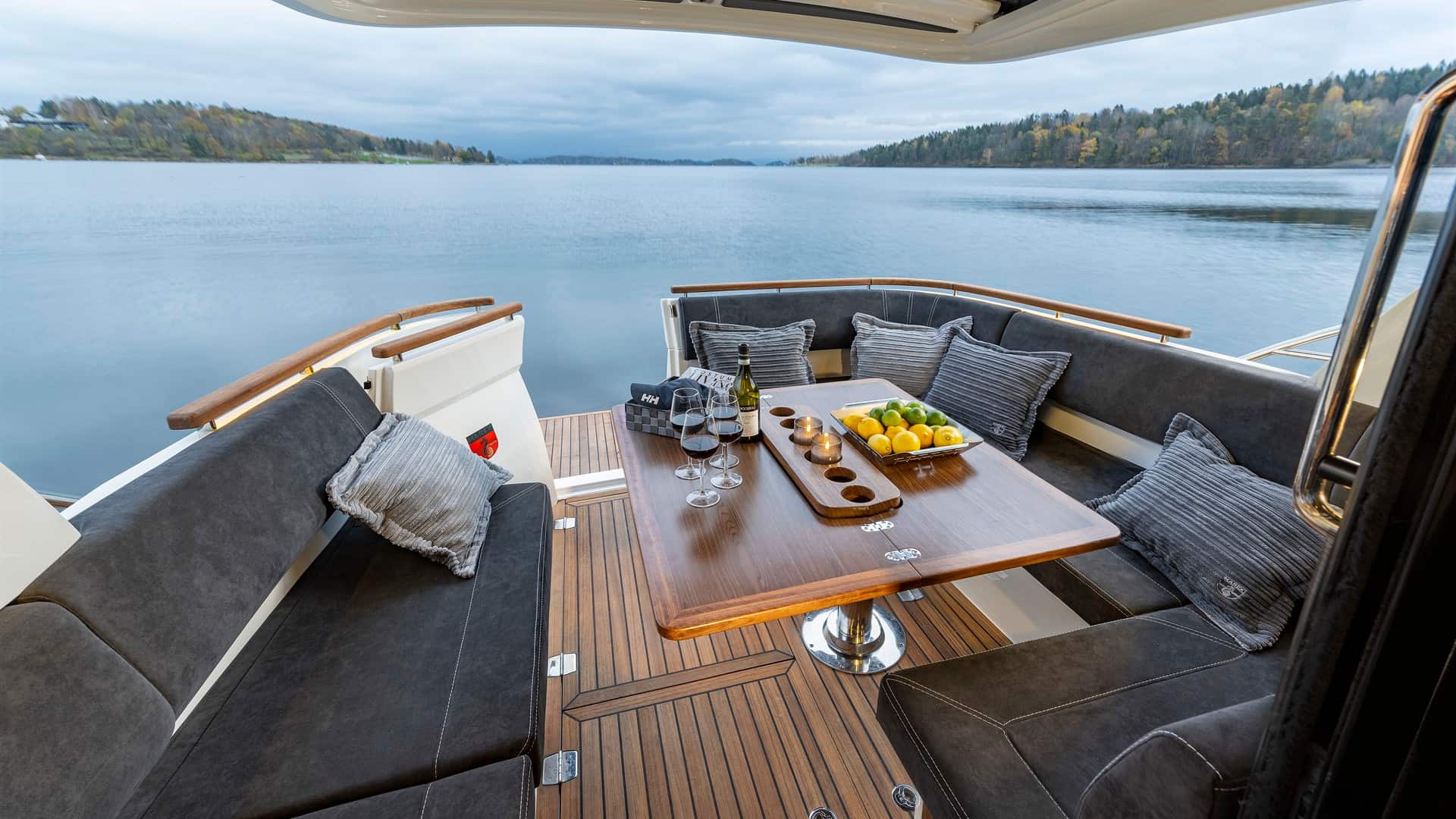 Blick auf das geräumige Cockpit der Marex Scandinavia 330 mit Holztisch, Sofas und Seeblick.