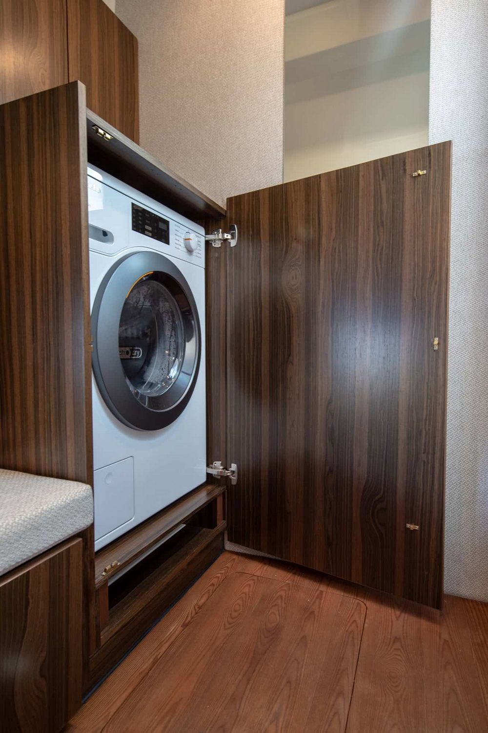 Wbudowana pralka automatyczna w drewnianej szafce na jachcie Marex 440 Gourmet Cruiser, z otwartymi drzwiczkami.