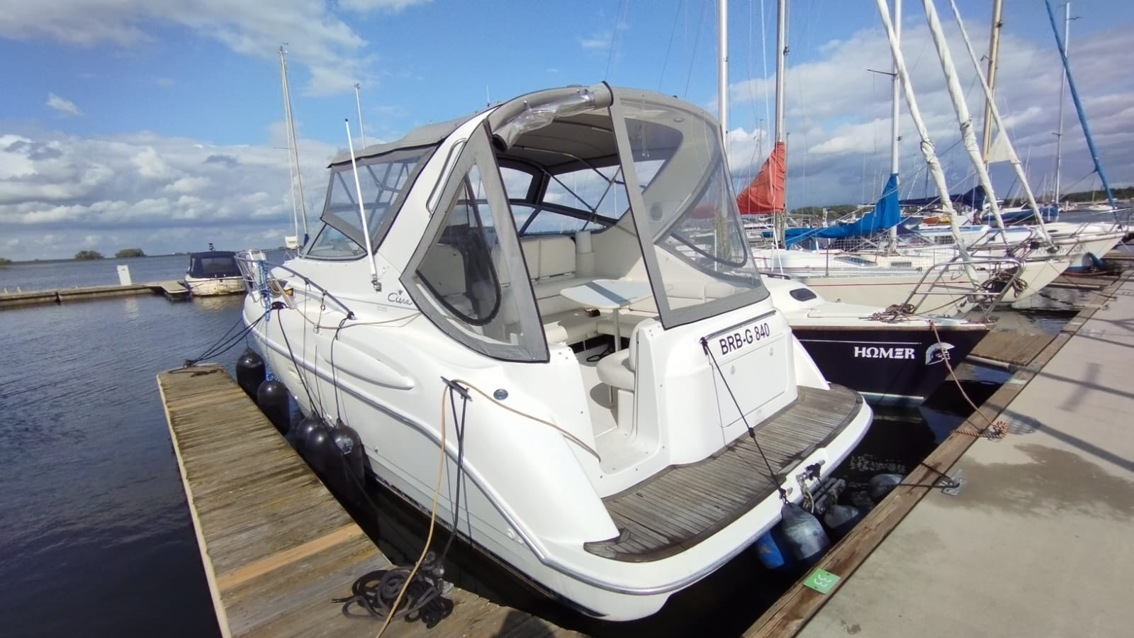 View of the stern and cockpit of the Bayliner 3055 motorboat moored at a wooden jetty, with a new grey cabrio bimini.