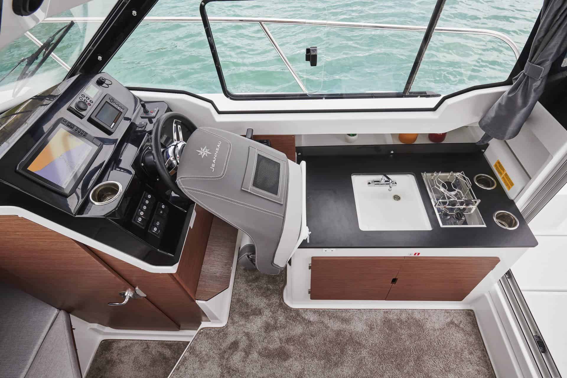 Blick auf den Steuerstand mit Elektronik und die Kombüse mit Kochstelle und Spüle im Inneren der Jeanneau Merry Fisher 795 Serie 2.