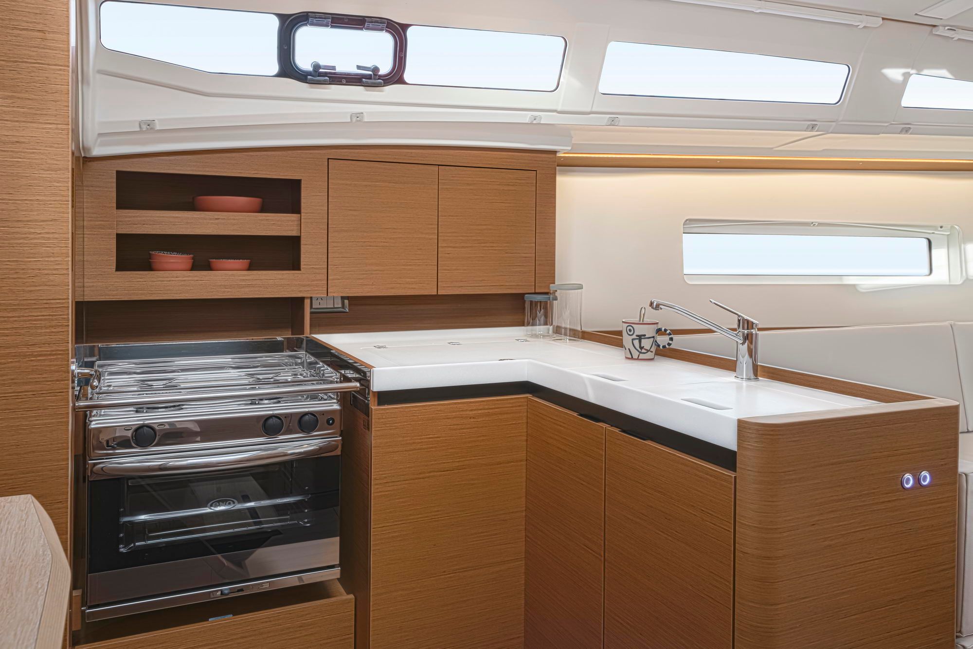 Kombüse der Segelyacht Jeanneau Sun Odyssey 380 mit Herd, Backofen und Spüle, umgeben von Holzschränken.