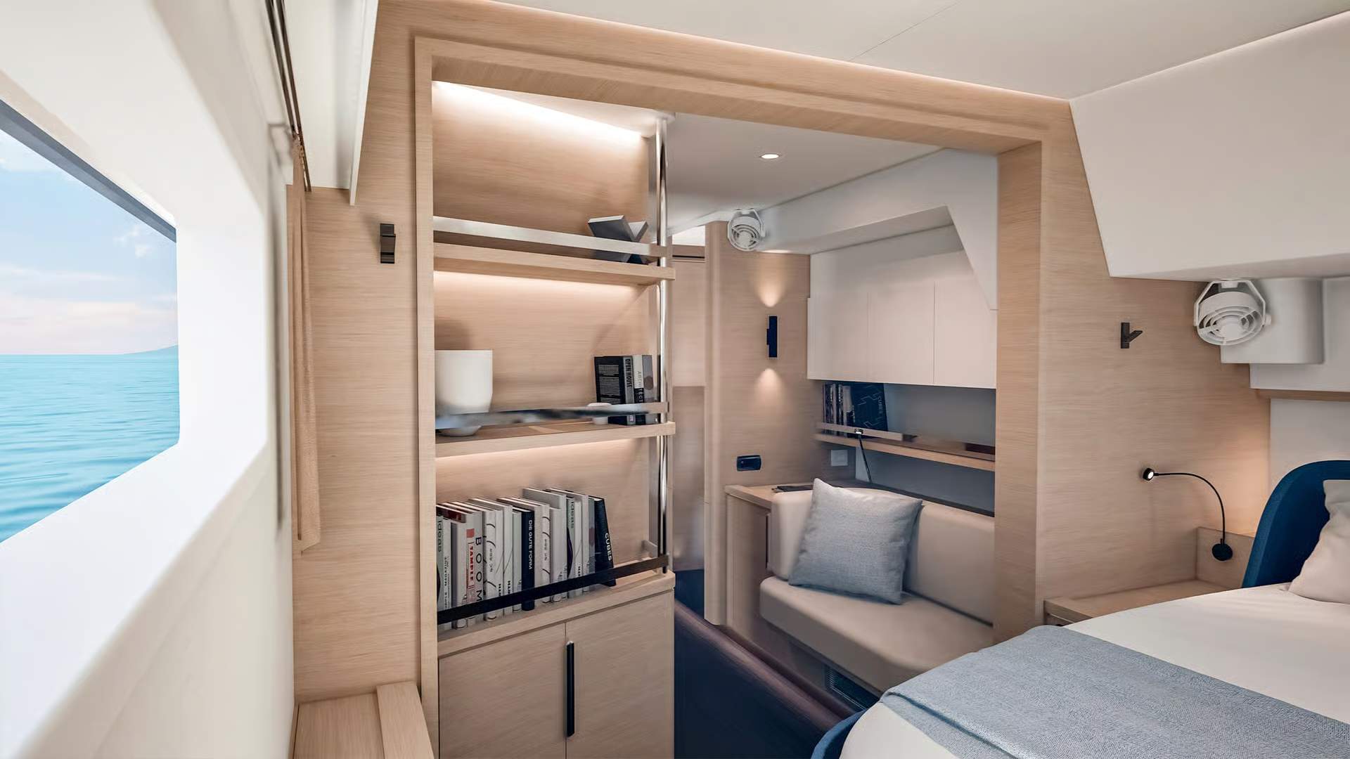 Innenraum der luxuriösen Eignerkabine des Katamarans Fountaine Pajot FP55 mit Bett, Sofa, Regalen und Meerblick durch das Fenster.