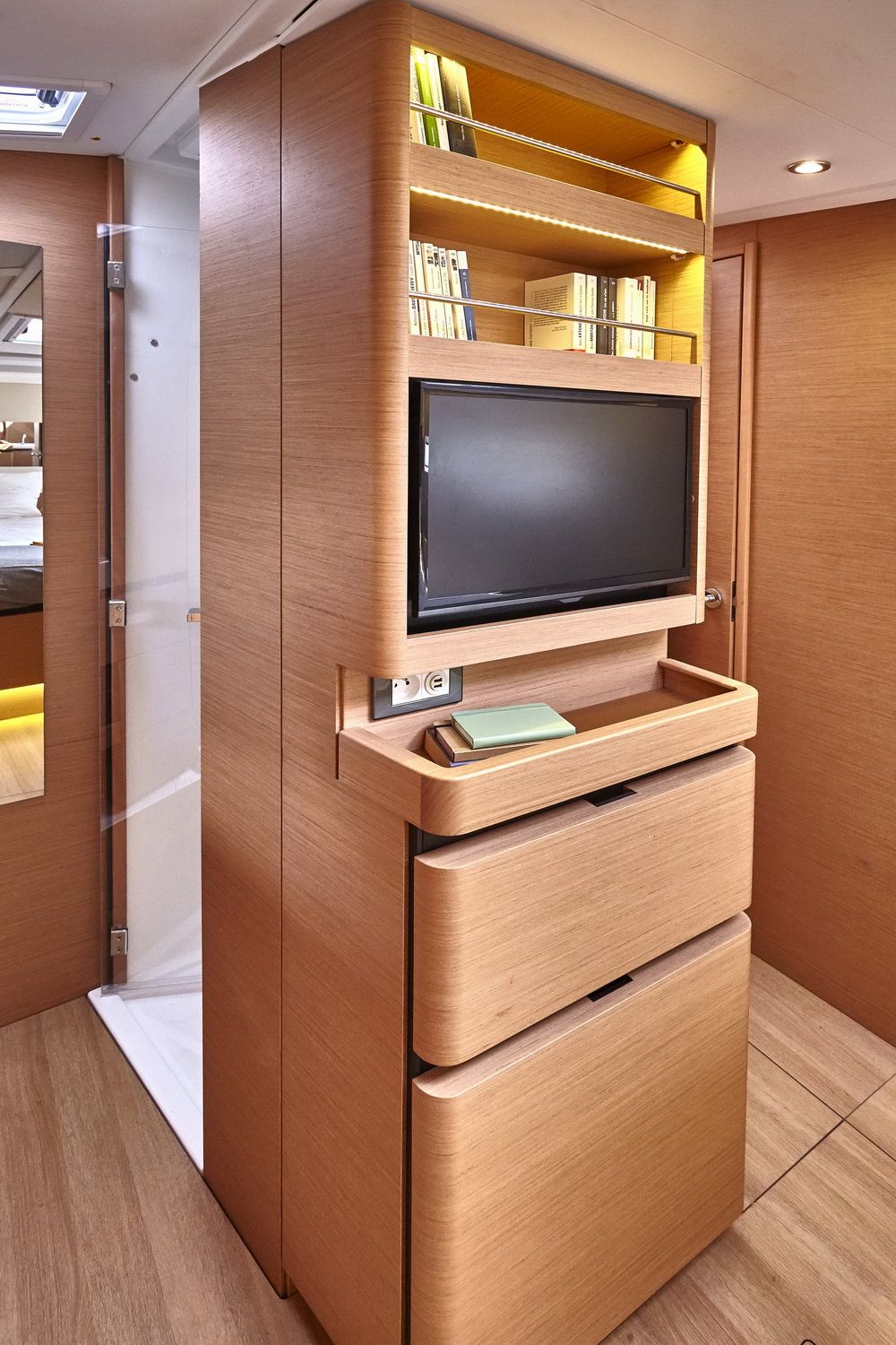 Wbudowany telewizor i półki na książki w apartamencie dziobowym Jeanneau Sun Odyssey 490.