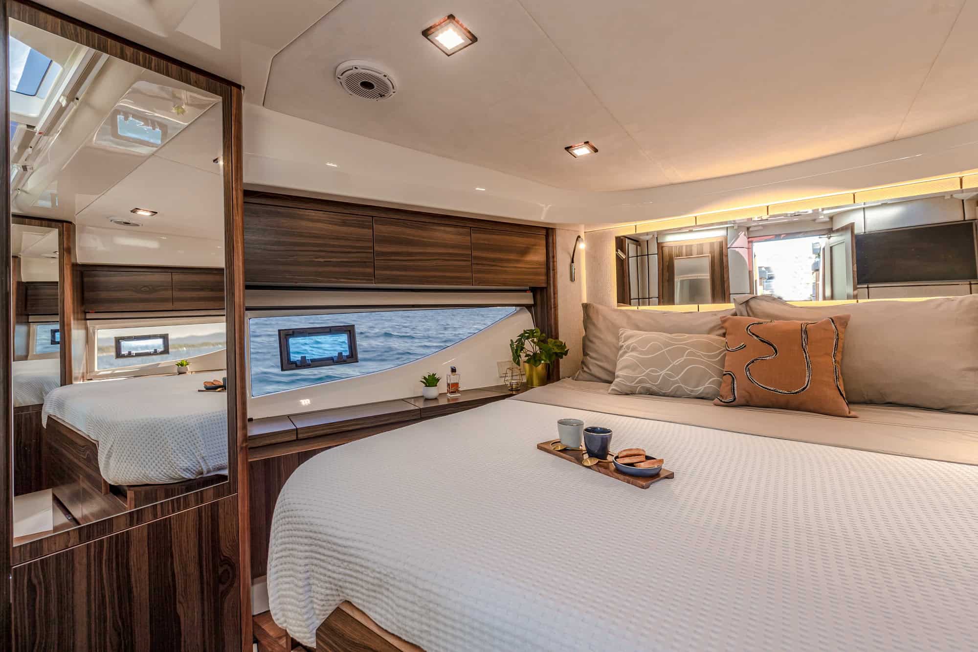 Spacious bow cabin on the Marex 440 Gourmet Cruiser with large bed, windows and wooden cabinets.
