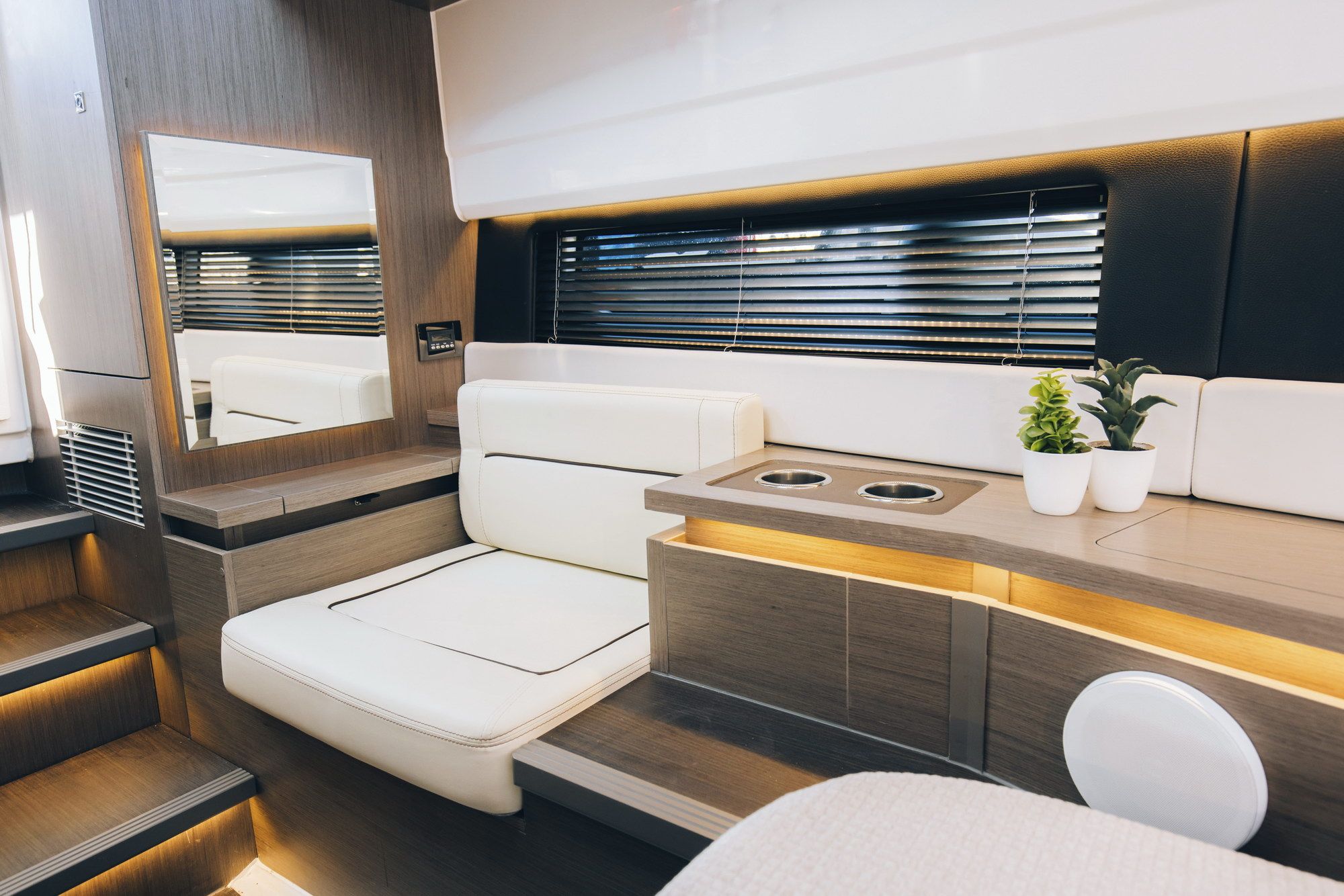 Luksusowy salon jachtu Wellcraft 38 Explorer z białymi kanapami, drewnianymi panelami, oświetleniem LED i lustrem.