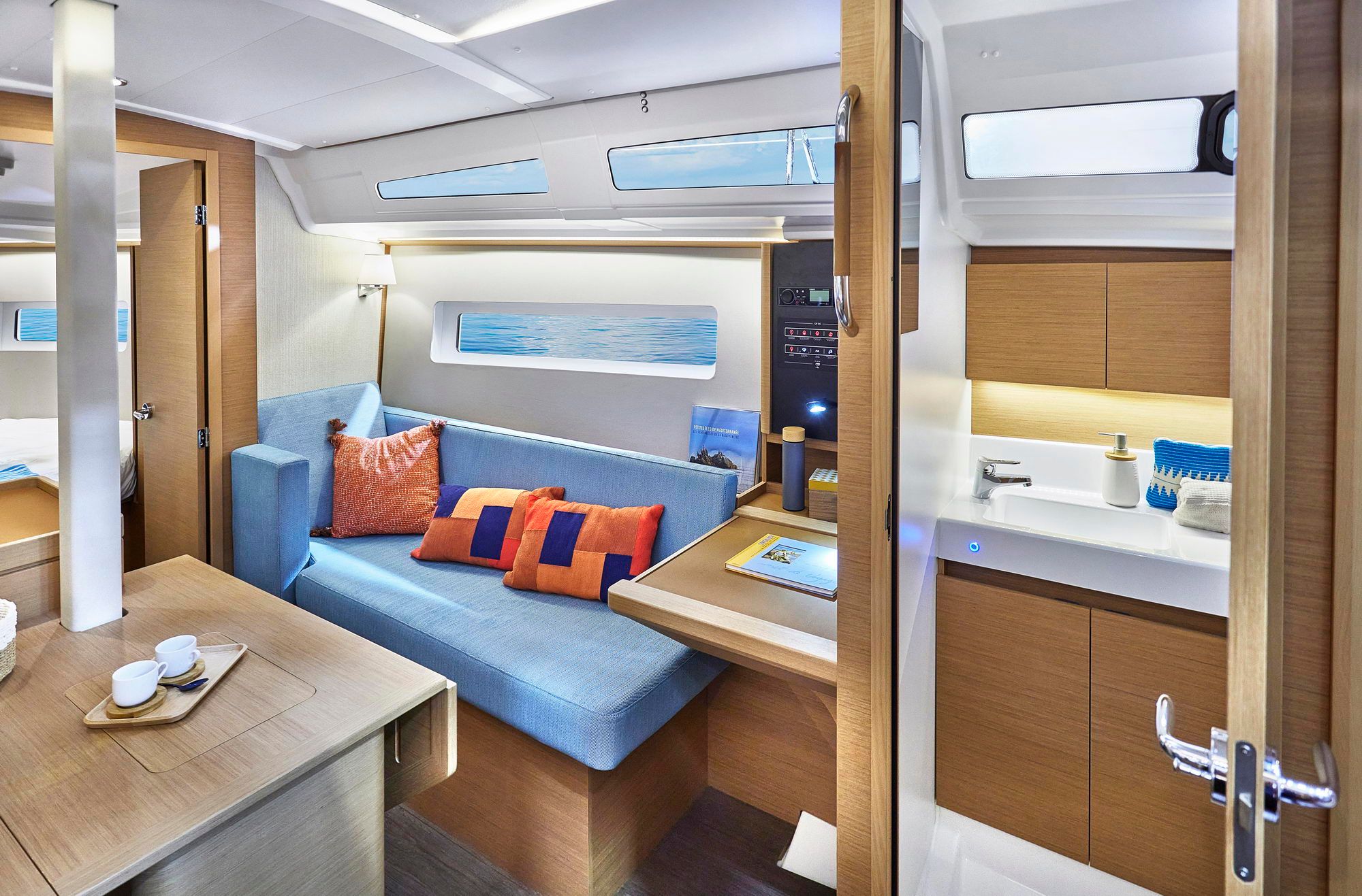 Wnętrze jachtu Jeanneau Sun Odyssey 380 z salonem, sofą, stołem i widokiem na łazienkę oraz kabinę.