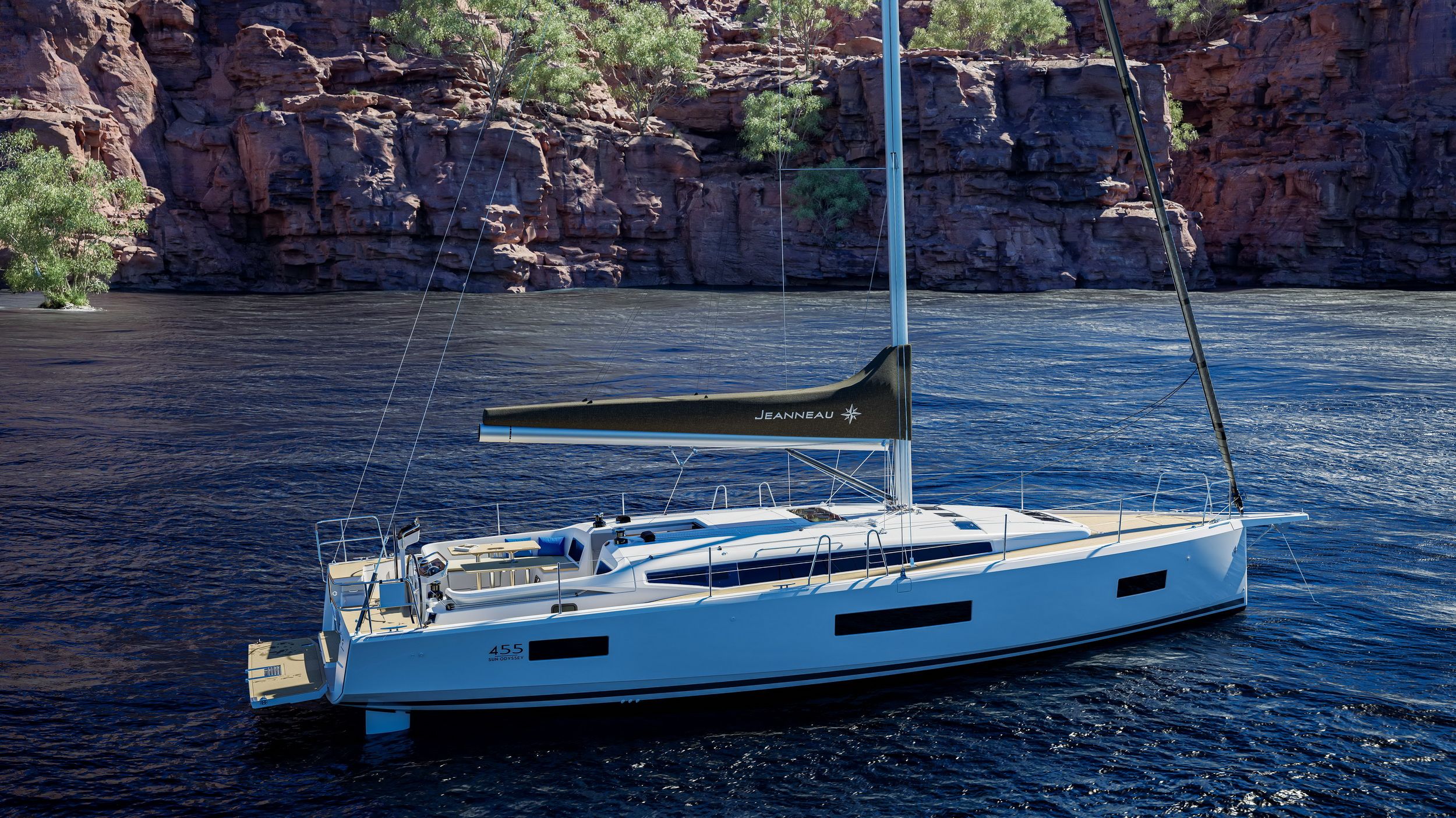 Jacht żaglowy Jeanneau Sun Odyssey 455 na spokojnej wodzie, widok z góry na rufę i pokład. W tle skaliste wybrzeże.