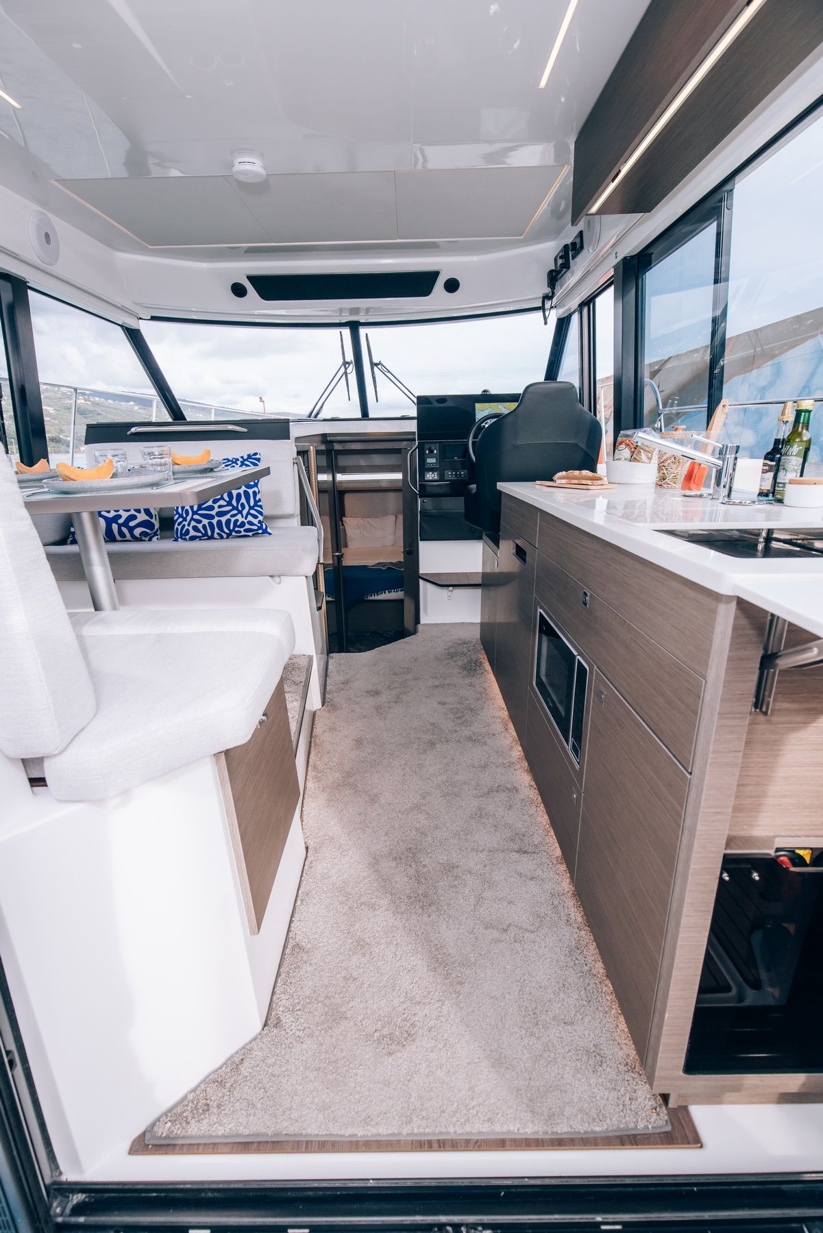 View of the saloon, galley and helm station inside the Jeanneau Merry Fisher 1095 Fly Serie2 motor yacht.