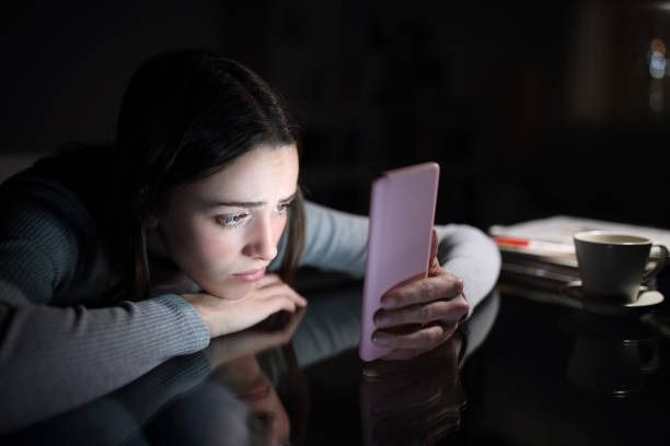 woman looking at her phone in a dark room