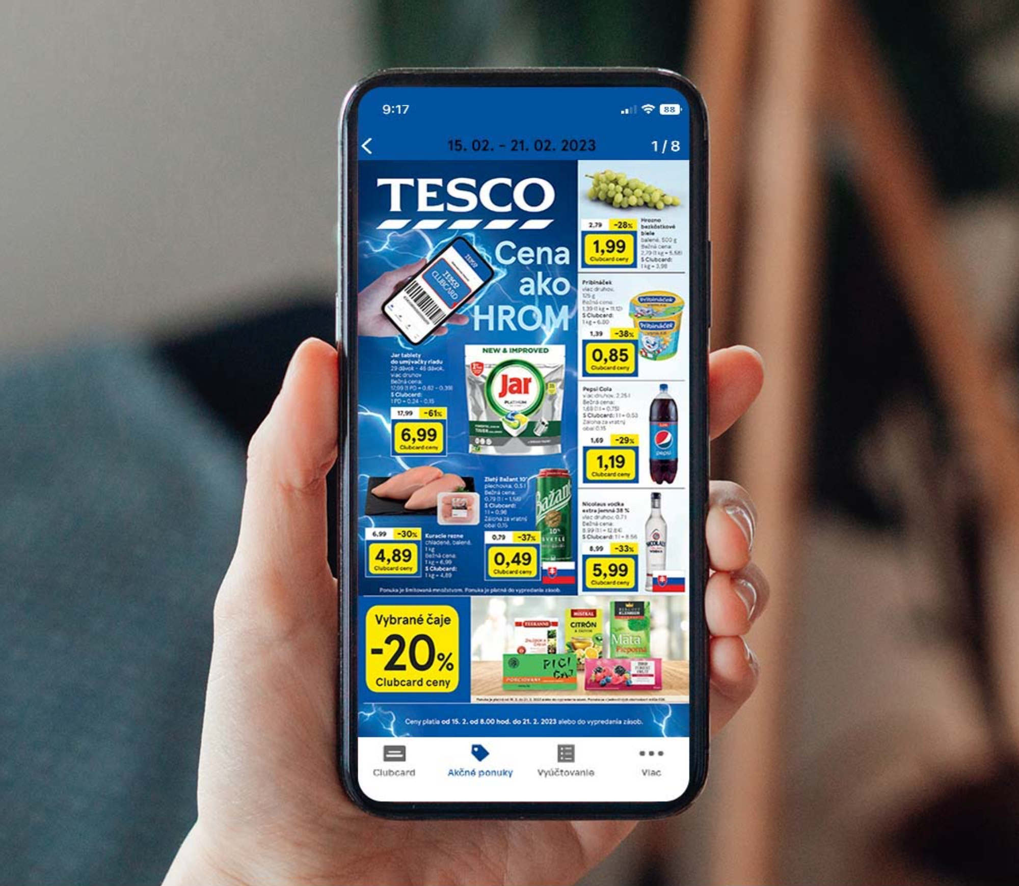 The leaflet inside the Clubcard app, held in one hand: Cena ako HROM over a lightning background, with the week’s prices tiled beneath it.