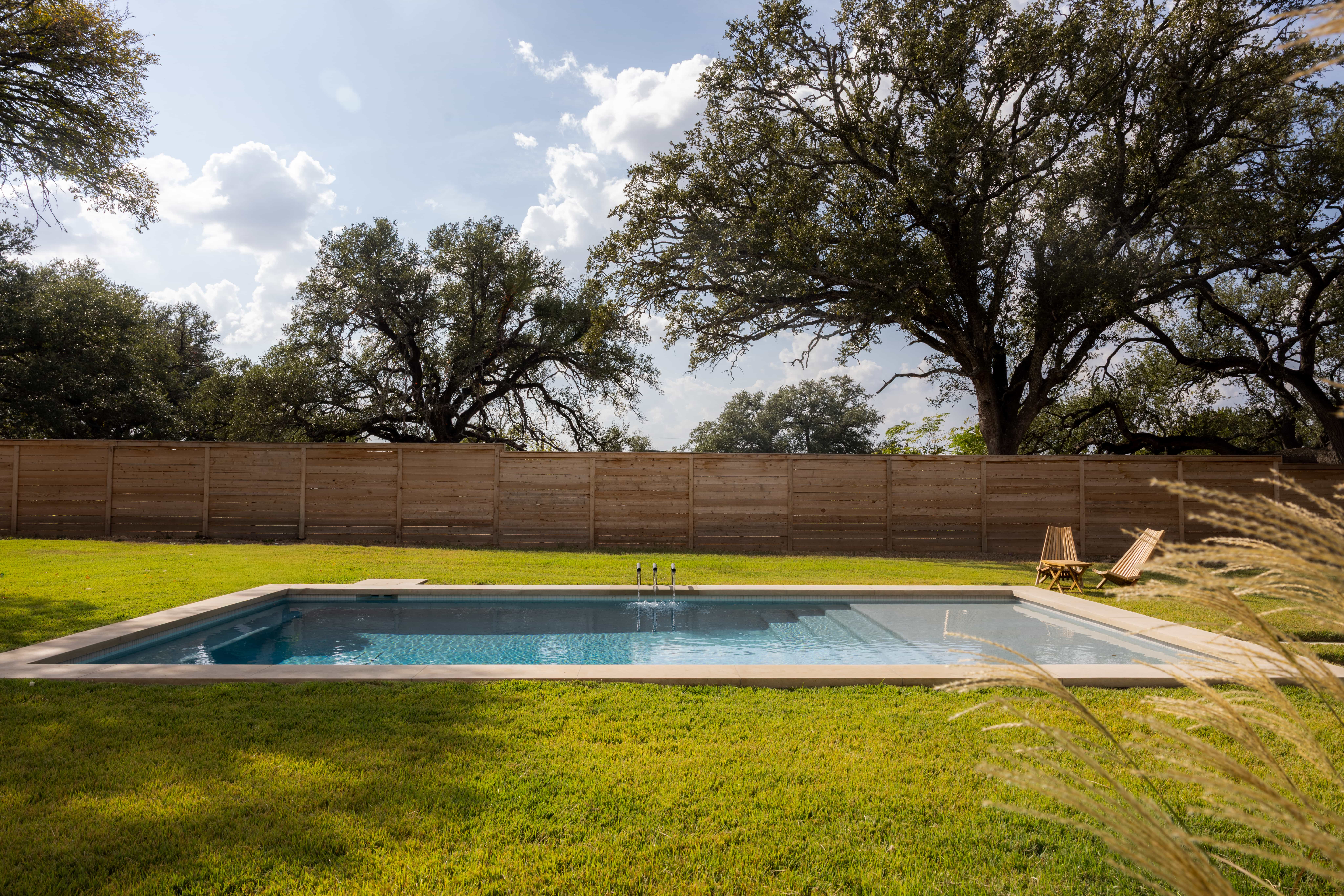 Golden Hour Pools Grand in Waco, featuring couple relaxing on tanning ledge and gunite plaster finish