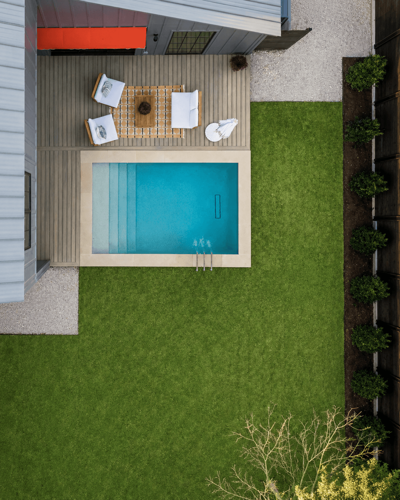 Golden Hour landscape aerial view of gunite pool with Lueders coping, composite deck, and green lawn