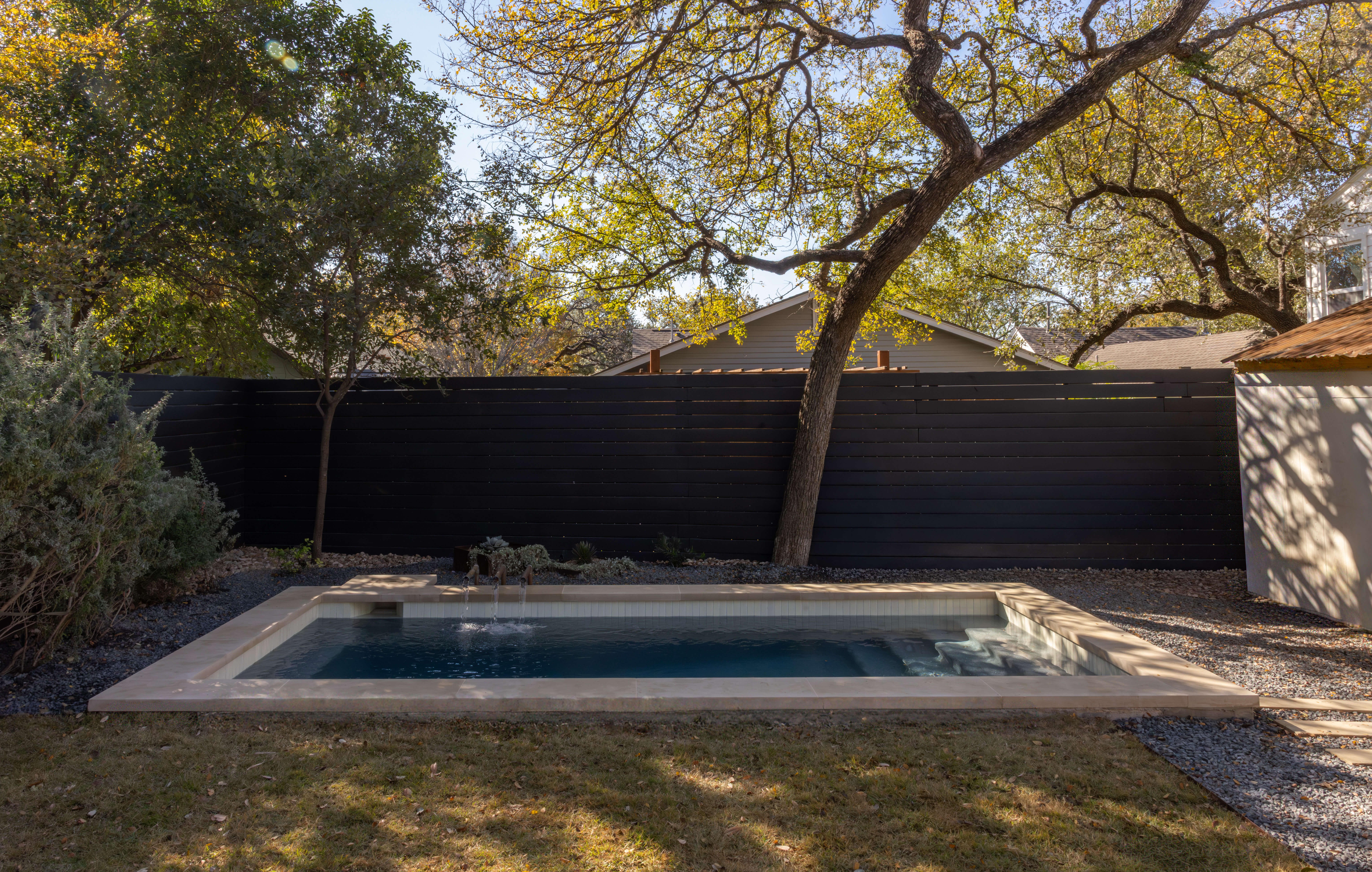 Golden Hour Pools Classic in Austin, featuring pool with black fence and fall foliage and gunite plaster finish
