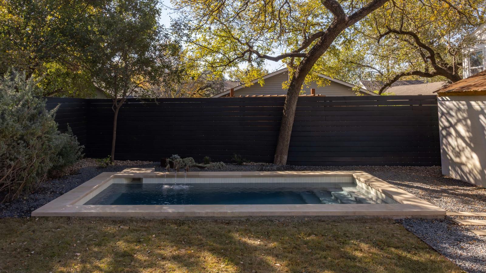 Golden Hour Pools Classic in Austin, featuring pool with black fence and fall foliage and gunite plaster finish