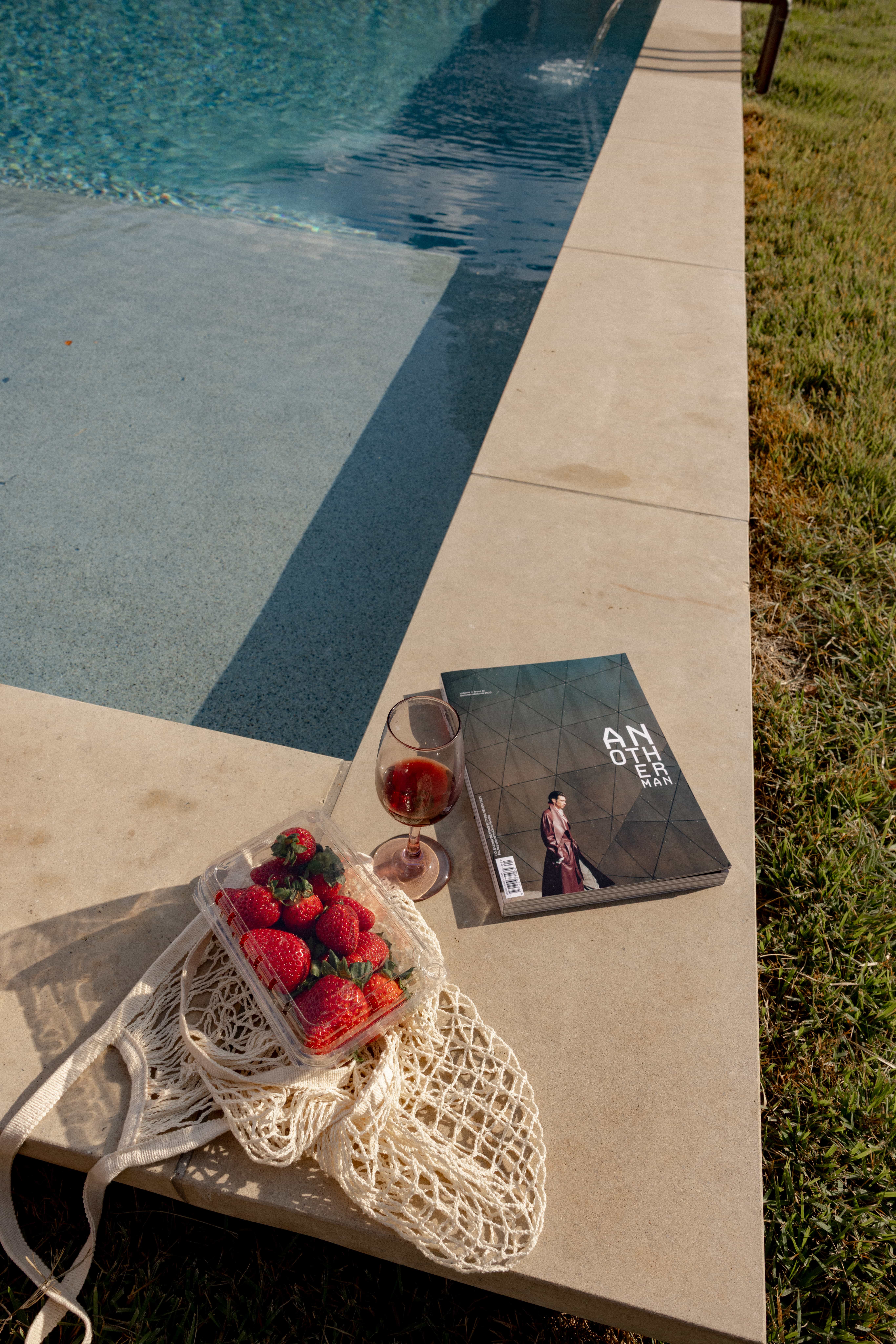 Golden Hour Pools Grand in Waco, featuring strawberries rosé and magazine on pool edge and gunite plaster finish