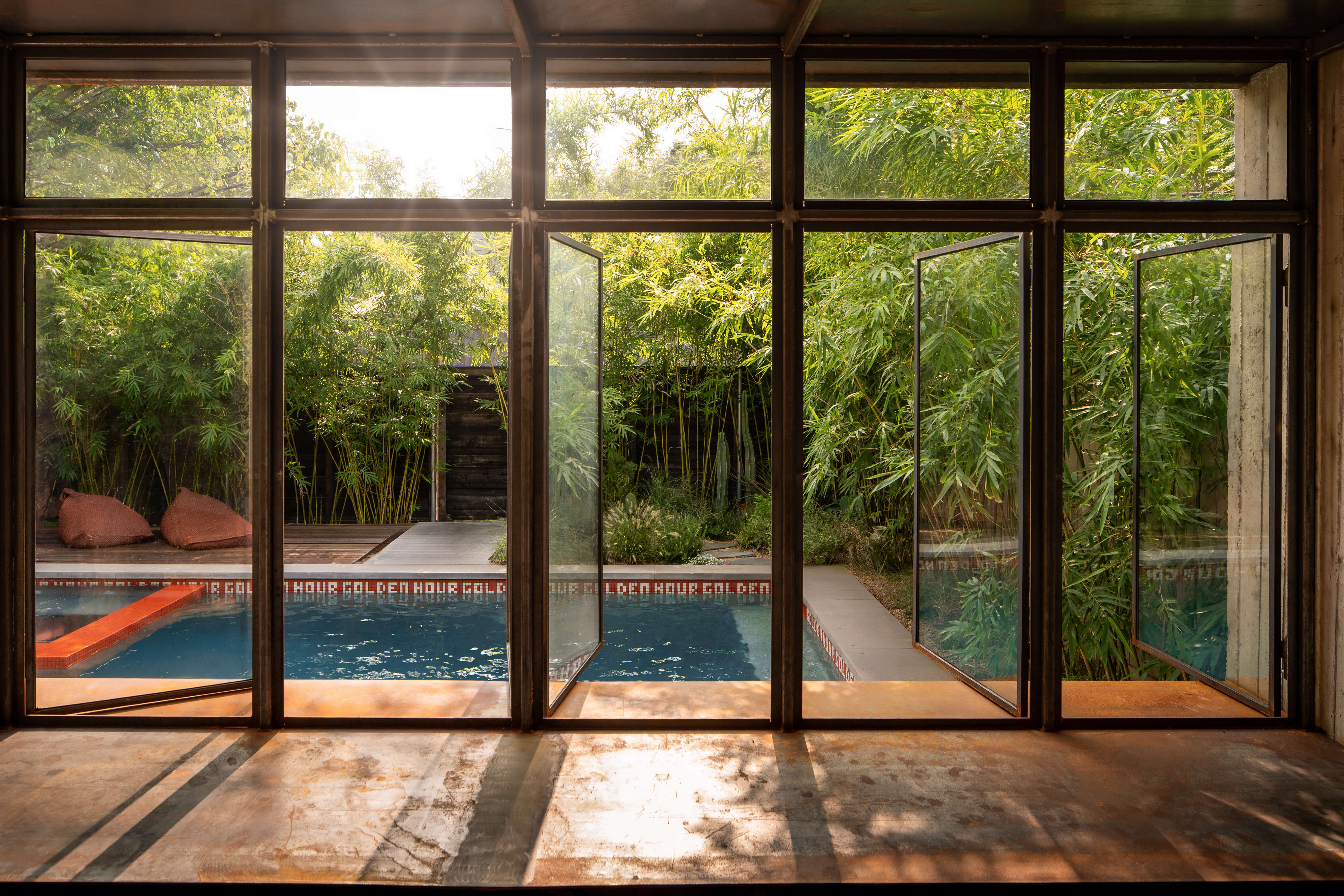 View down the Grand pool through open glass doors of the Dallas pool house