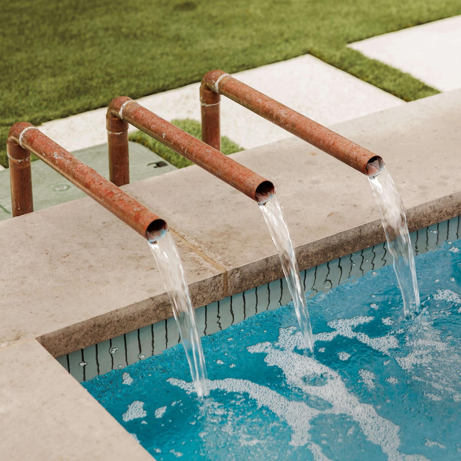 Golden Hour Pools Mini in Dallas, featuring copper scuppers pouring over dark tile and gunite plaster finish