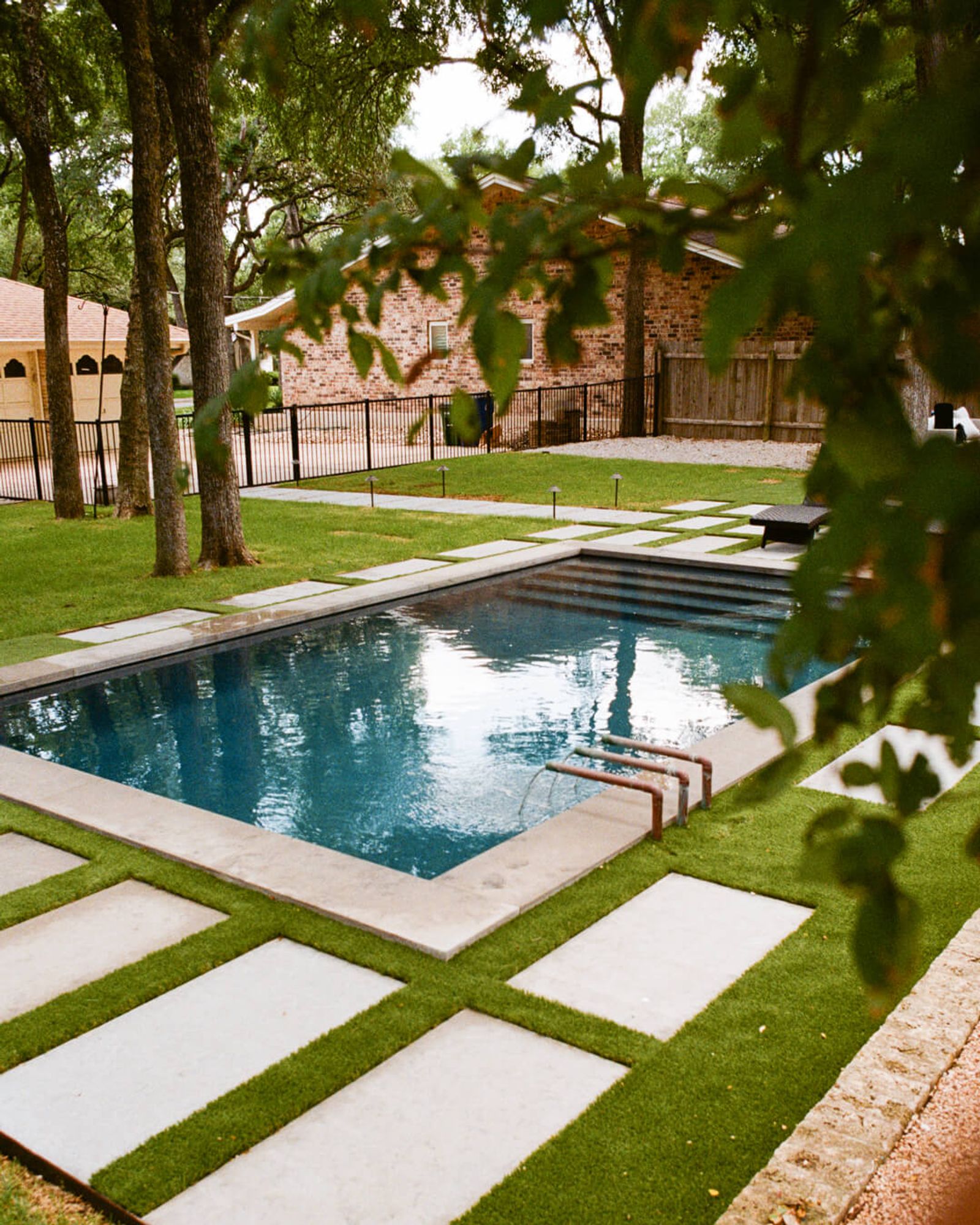 Golden Hour Pools Grand in San Antonio, featuring oak canopy framing pool and brick home and gunite plaster finish