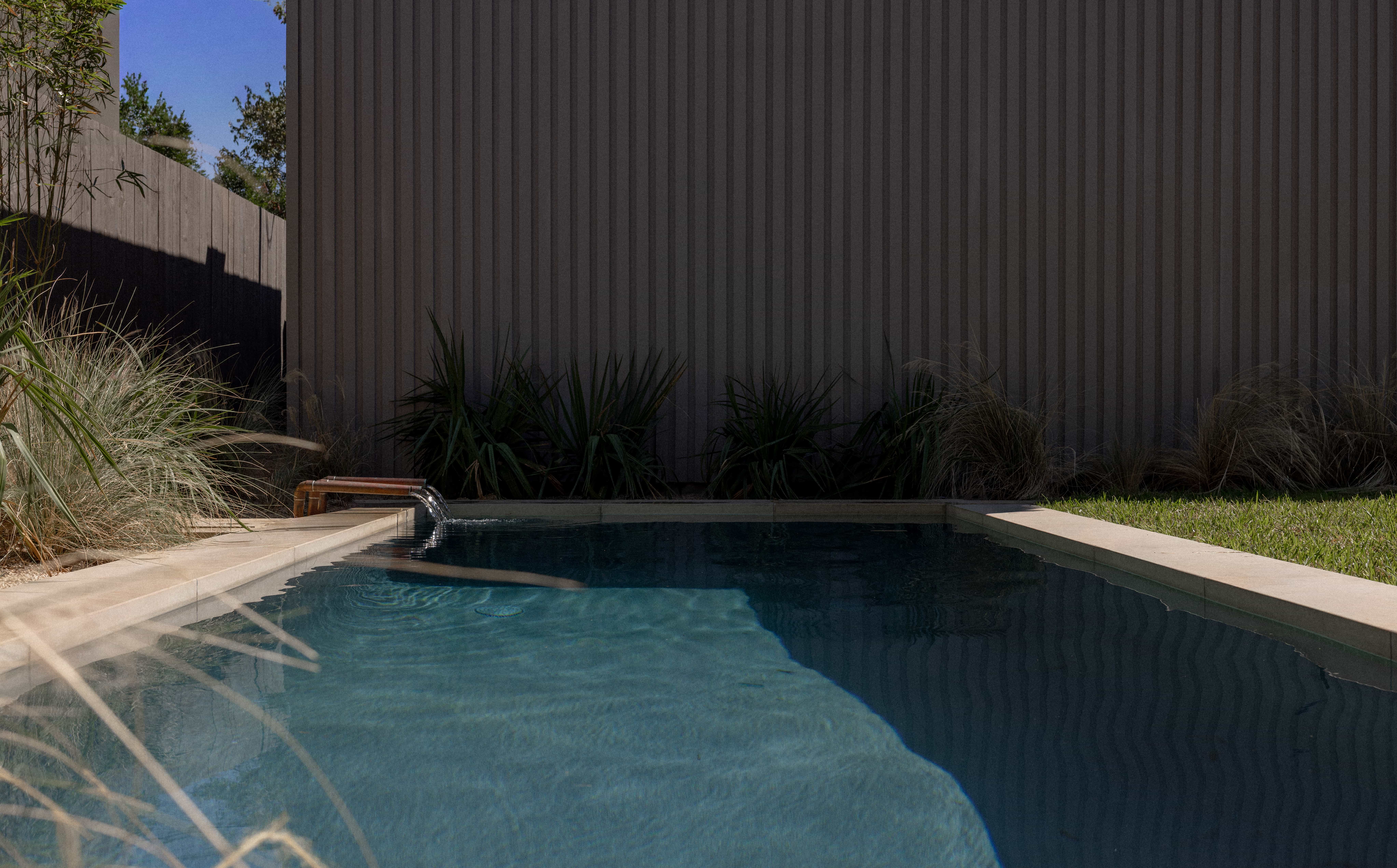 Golden Hour Pools Classic in Austin, featuring fountain stream with grasses behind and gunite plaster finish
