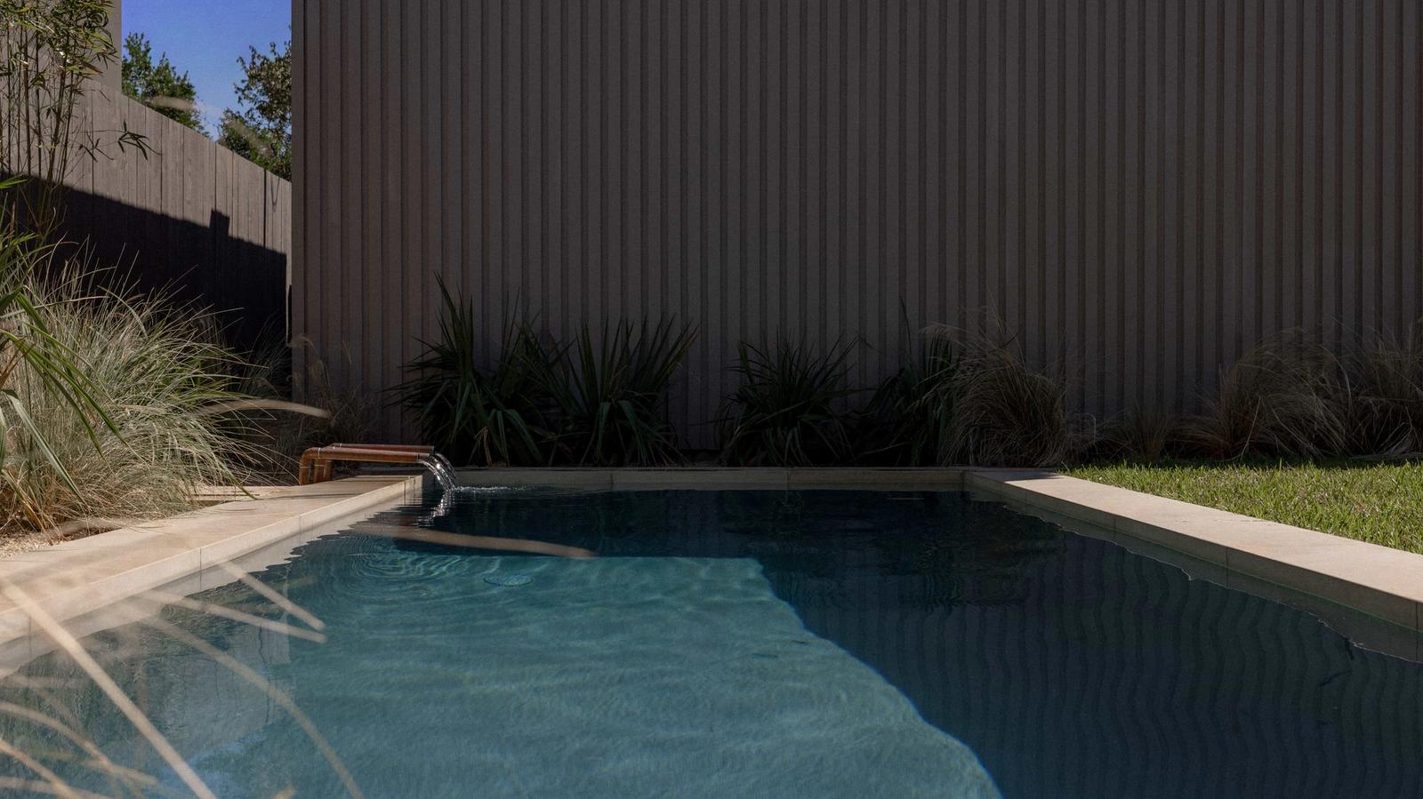 Golden Hour Pools Classic in Austin, featuring fountain stream with grasses behind and gunite plaster finish