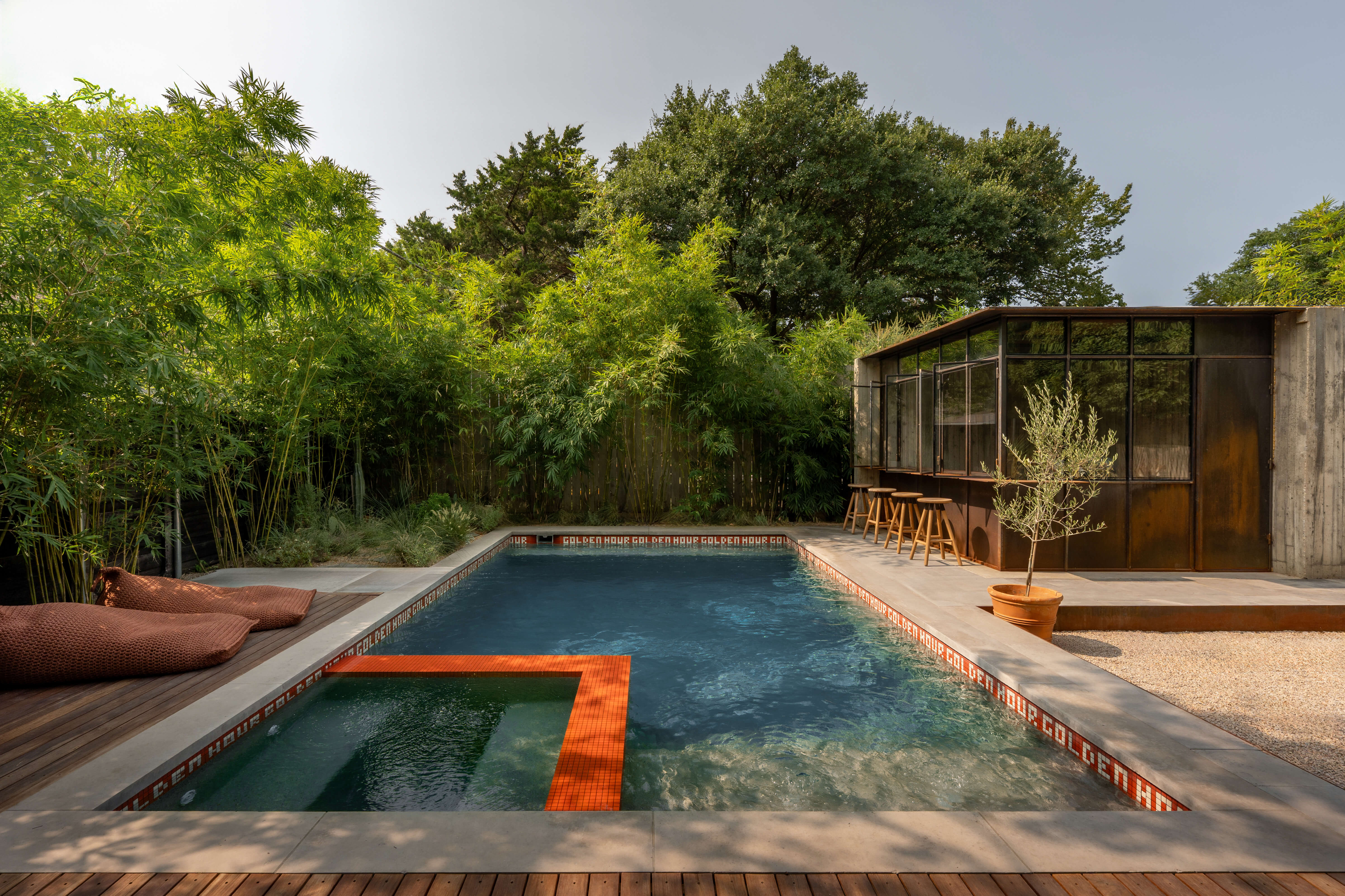 Dallas pool house Grand pool with attached spa, corten steel cabana, and bamboo landscaping