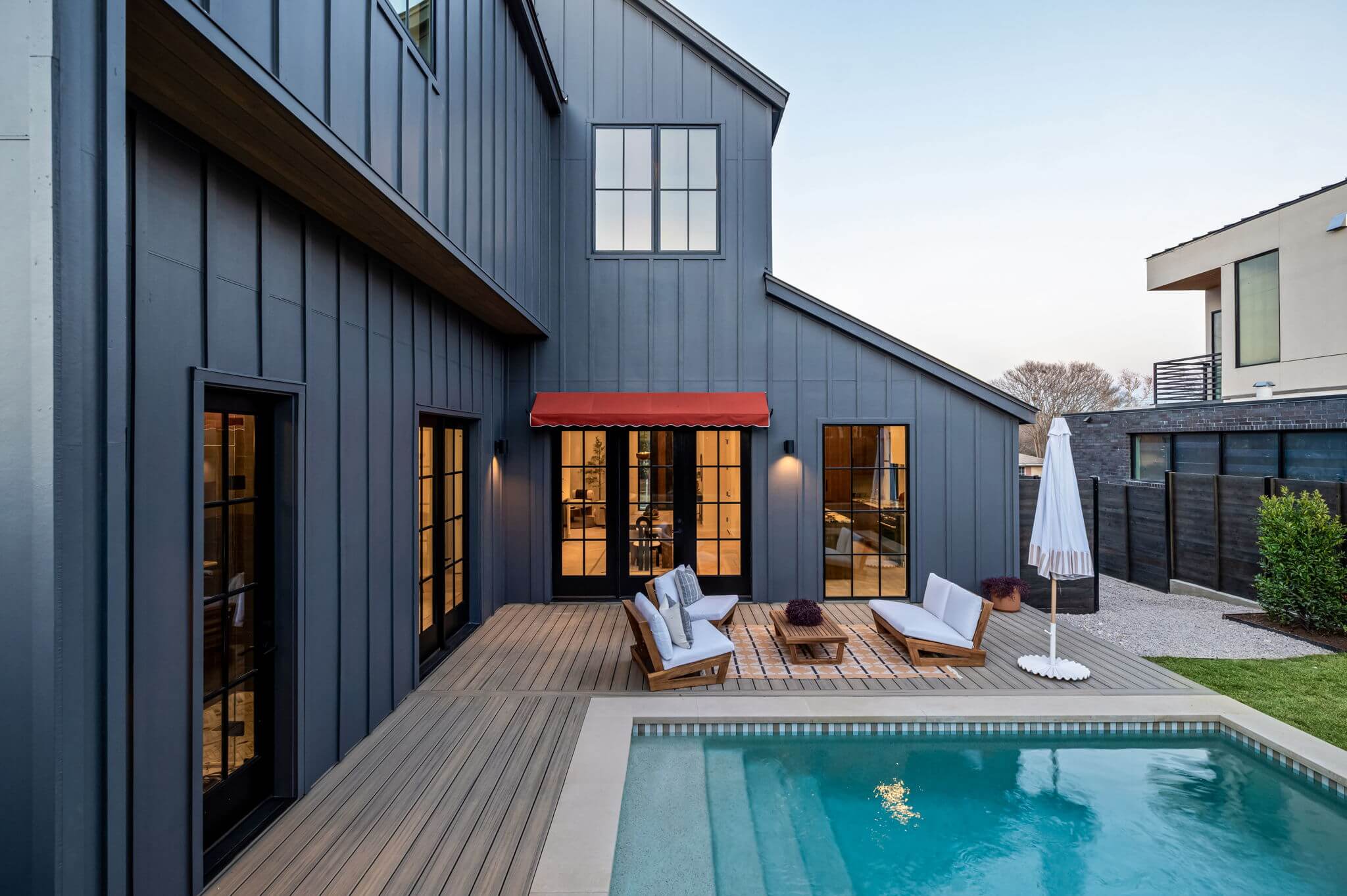 Golden Hour Pools Classic in Austin, featuring pool and composite deck at dusk with warm interior glow and gunite plaster finish
