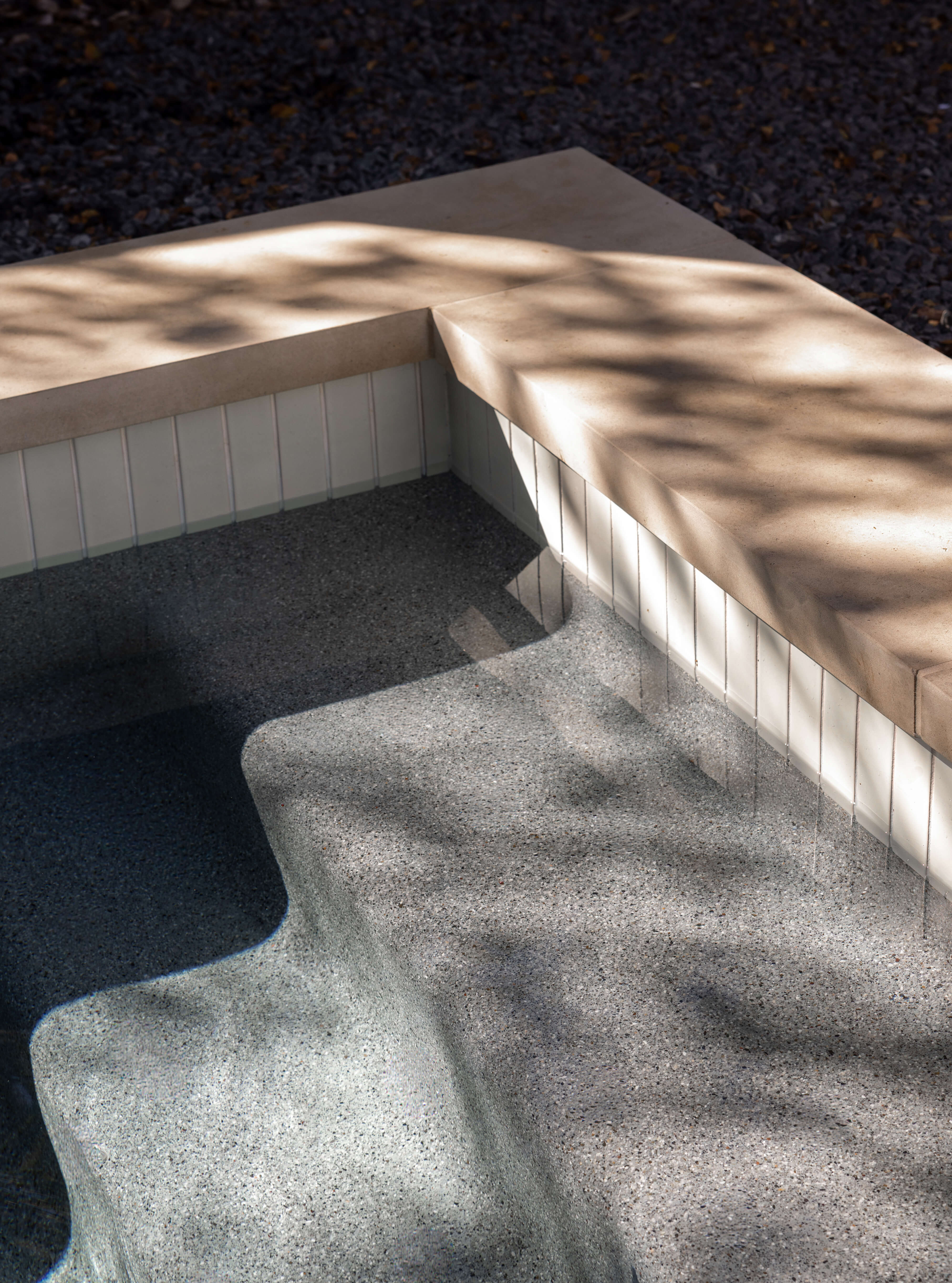 Golden Hour Pools Classic in Austin, featuring pool steps with waterline tile and tree shadows and gunite plaster finish