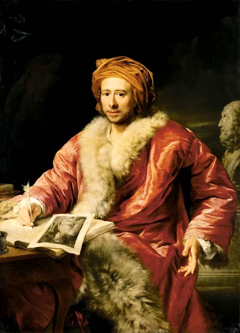 A portrait painting of Johann Joachim Winckelmann seated at a desk, wearing a bright red, fur-lined velvet robe and a matching turban. He is looking directly at the viewer while holding a quill pen, in the process of writing in a book that contains an illustration of a classical figure. To his side, a portion of a stone bust is visible, and the overall lighting is dramatic, emphasizing his presence against a dark, moody background.