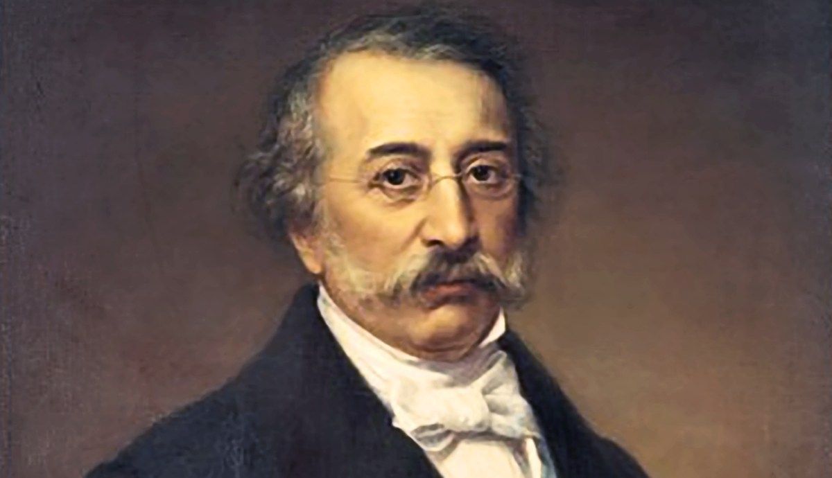 A painted portrait of Alexandros Mavrokordatos, featuring a mature man with thin glasses, a prominent mustache, graying hair, a white high-collared shirt with a cravat, and a dark jacket against a muted brown background.