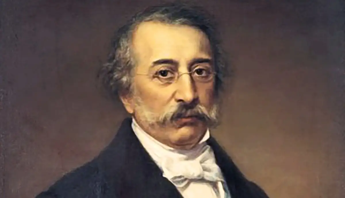 A painted portrait of Alexandros Mavrokordatos, featuring a mature man with thin glasses, a prominent mustache, graying hair, a white high-collared shirt with a cravat, and a dark jacket against a muted brown background.
