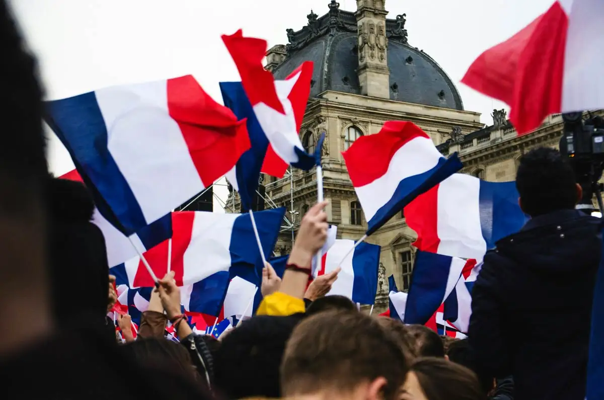 people holding french flags in front of the Louvre
