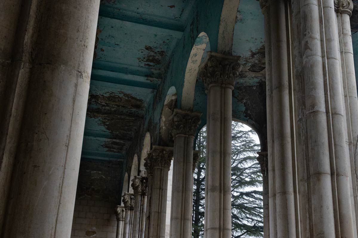 The decaying grandeur of Sanatorium Medea: towering stone columns stand beneath a fading turquoise ceiling, capturing the haunting beauty of Tskaltubo’s abandoned Soviet-era architecture.