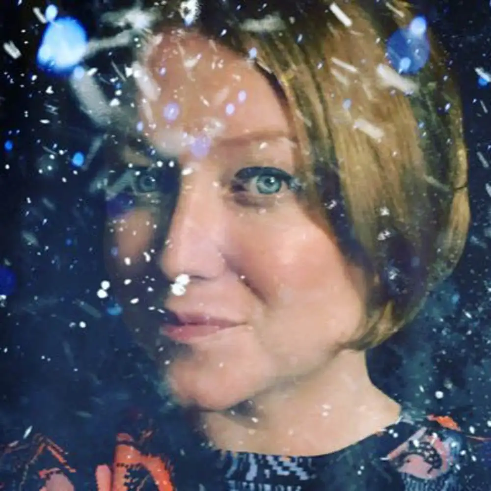 A close-up portrait of author Laura Jenkinson-Brown overlaid with a digital filter of white and blue glowing flecks.