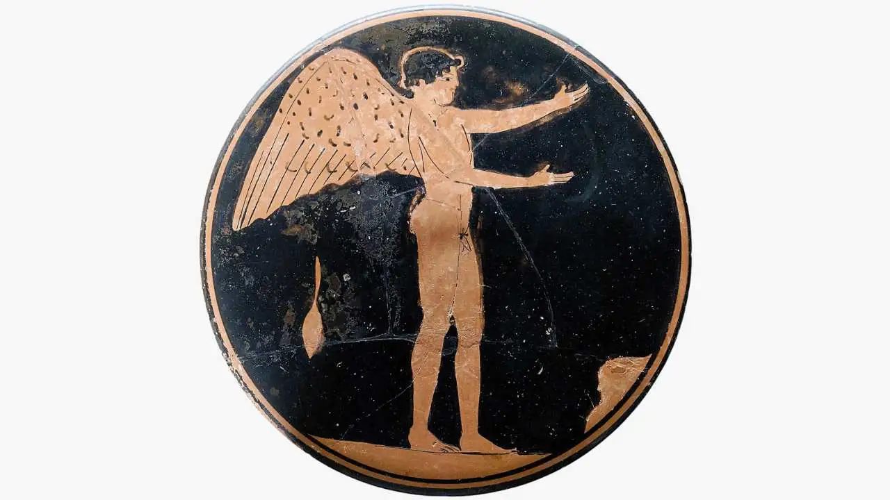 A circular piece of ancient Greek red-figure pottery. It depicts a naked, winged youth standing in profile on a black background, with both arms reaching outward.