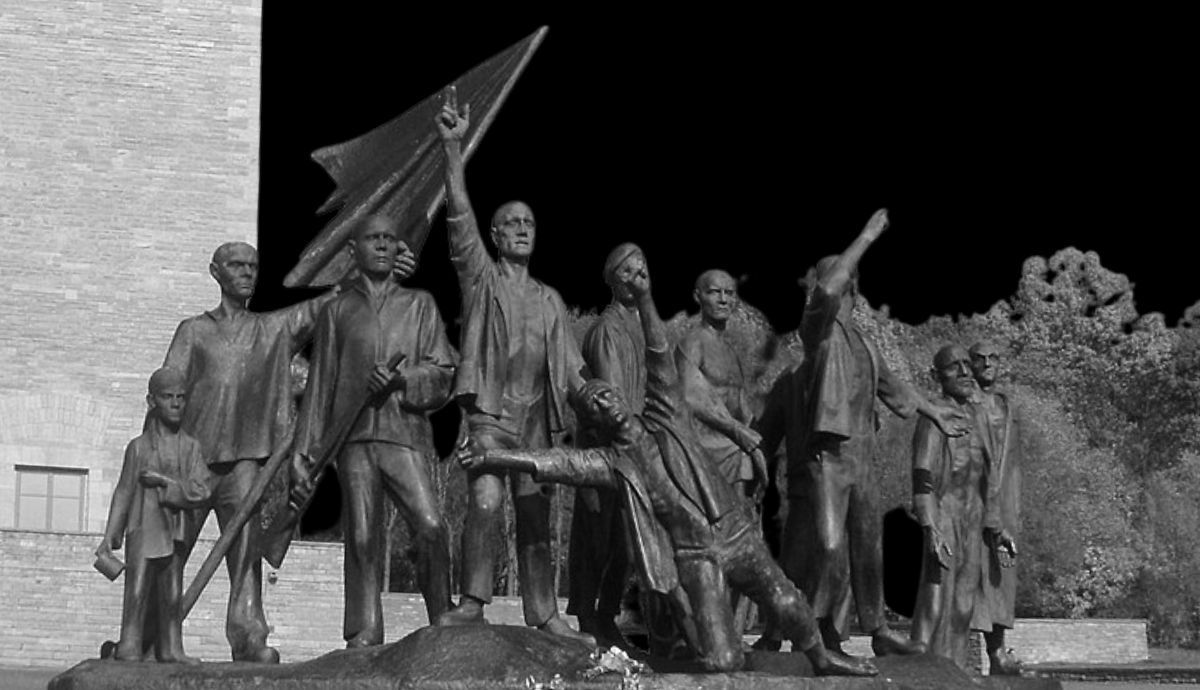 The bronze monumental sculpture by Fritz Cremer at the Buchenwald concentration camp memorial, depicting a group of resistance fighters and survivors under a dark sky.
