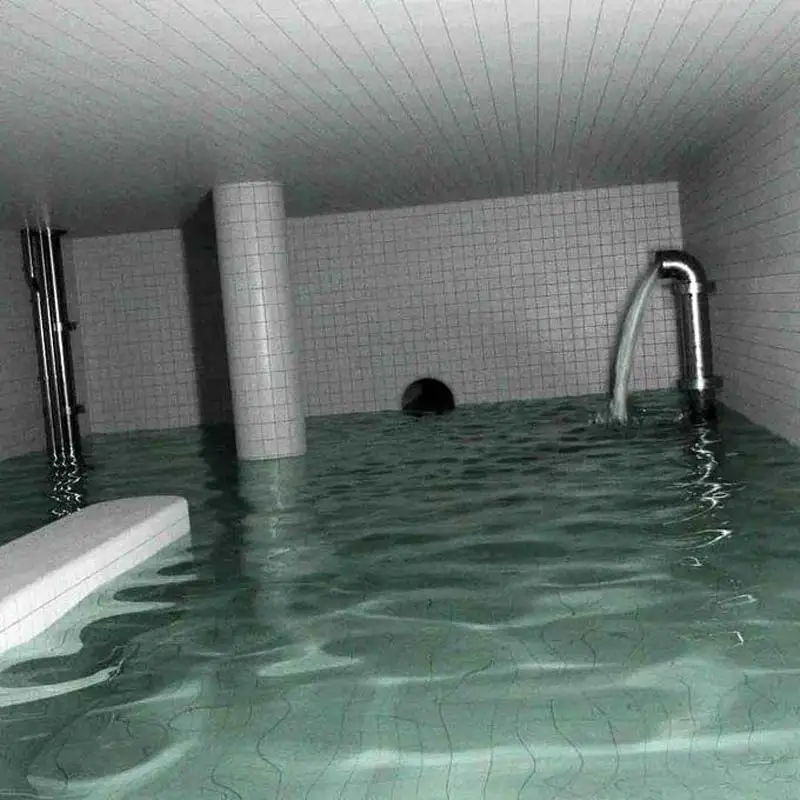 A flash photograph of an eerie, indoor pool room completely submerged in murky green water. The walls, ceiling, and structural pillars are entirely lined with white square tiles. A large metallic pipe on the right wall continuously discharges a stream of water into the pool, while a small, dark circular tunnel opening is visible on the far wall near the water's surface.